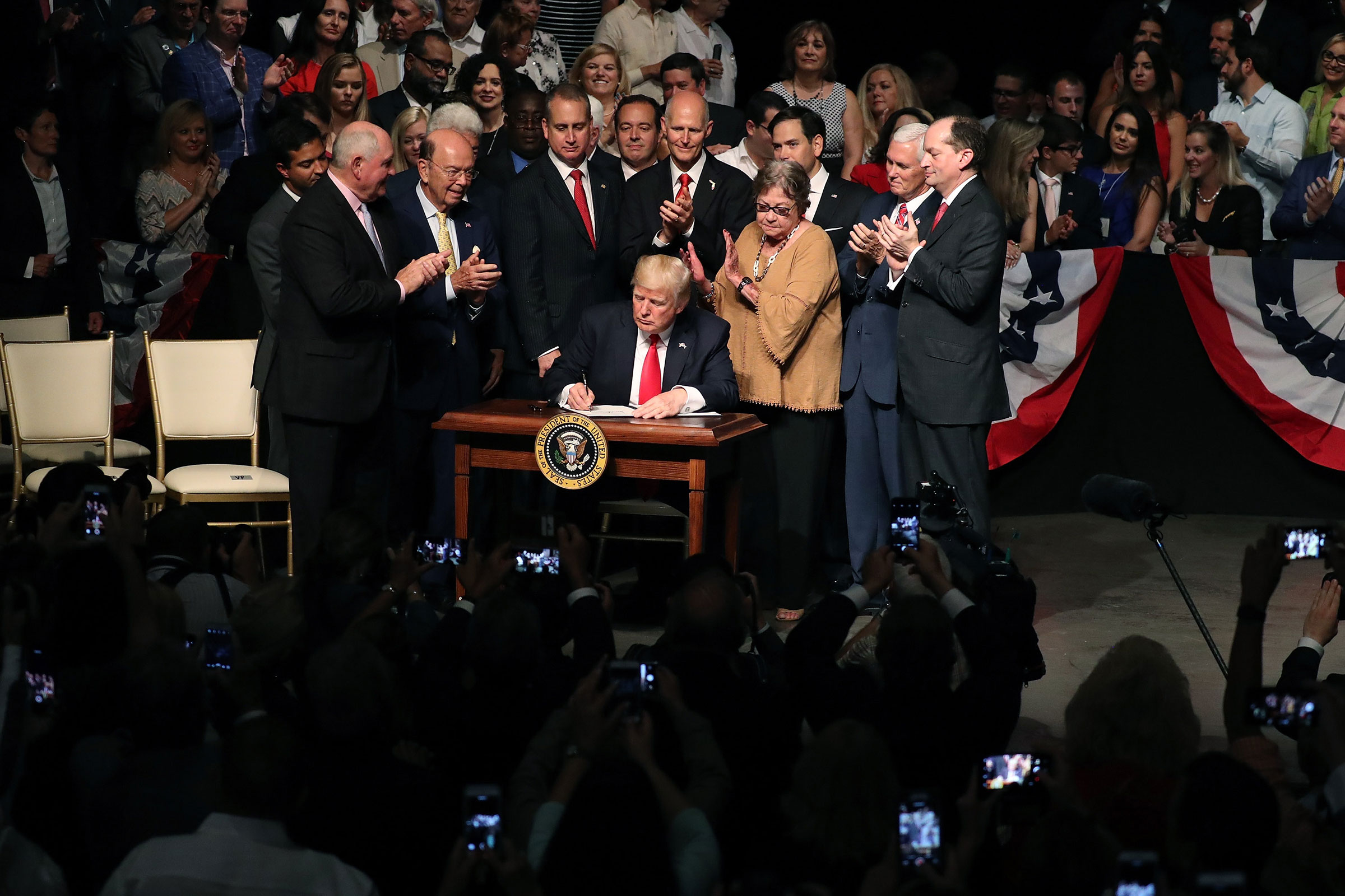 President Donald Trump signs policy changes he is making toward Cuba at the Manuel Artime Theater in the Little Havana neighborhood on June 16, 2017 in Miami, Florida. 