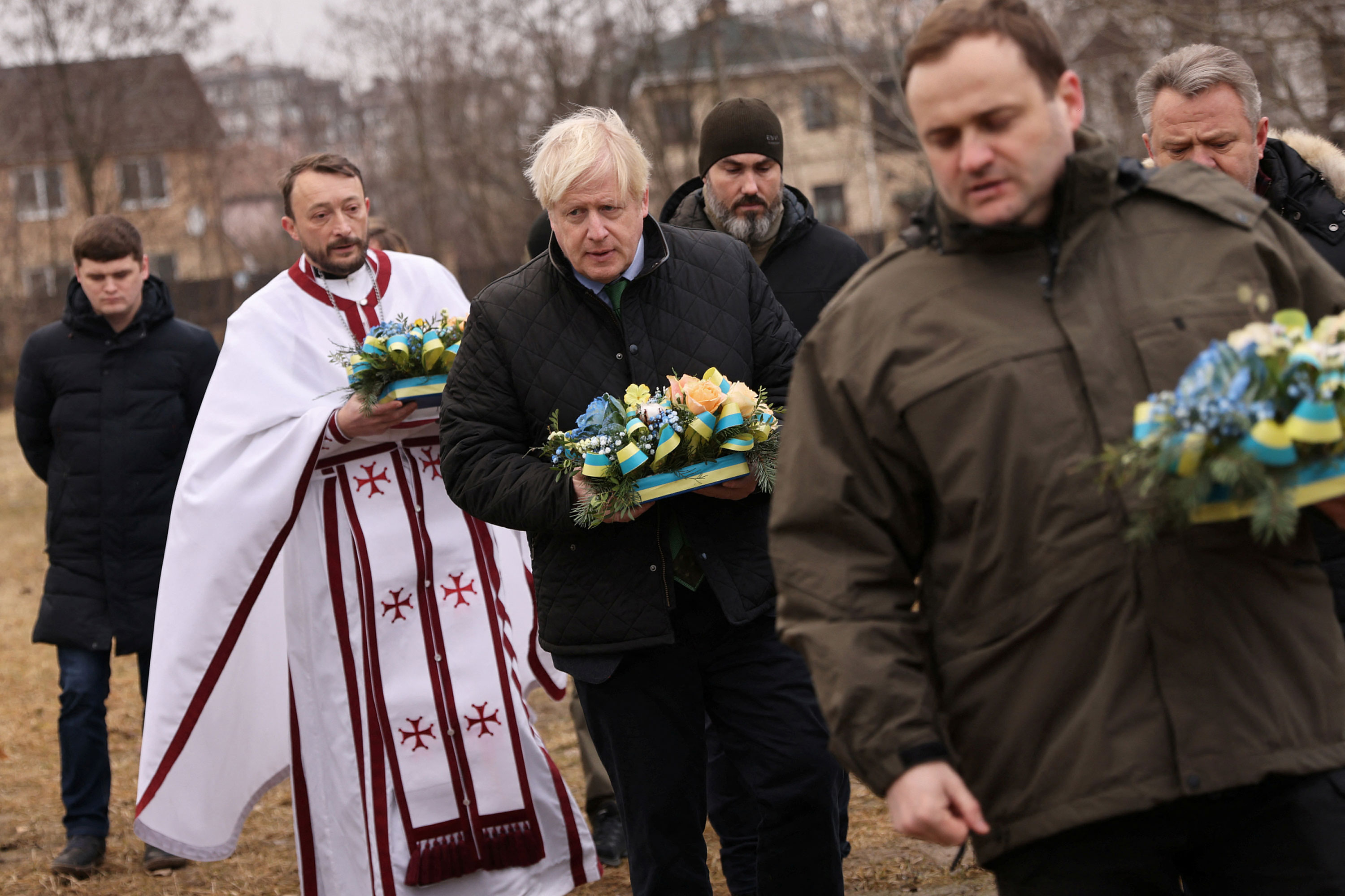 Former British Prime Minister Boris Johnson lays flowers to pay tribute to those killed during Russia's invasion of Ukraine as he visits the Church of Sviatoho Apostola Andriia Pervozvannoho in Bucha on Sunday. 