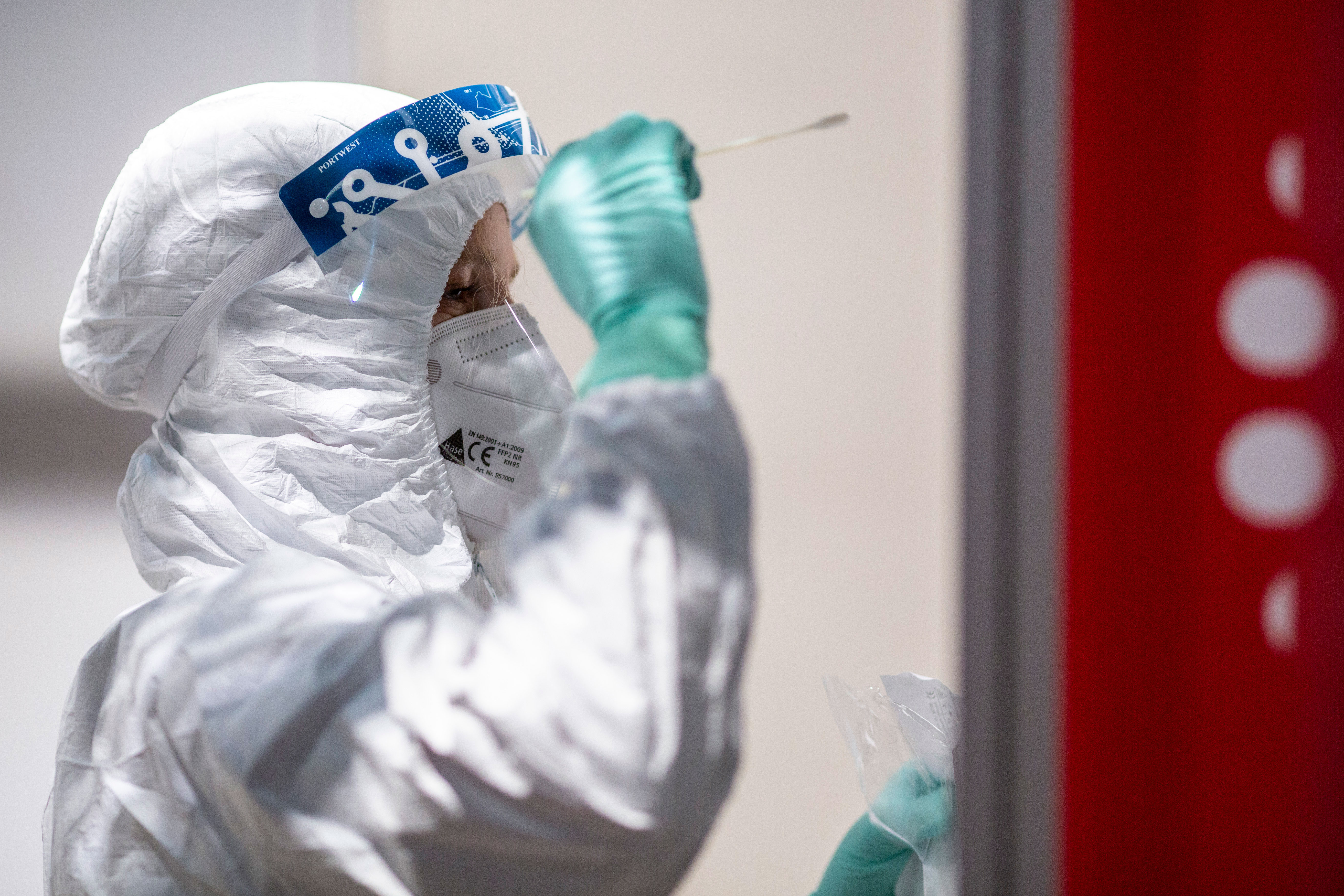 A medical worker in Schönefeld, Germany, takes a Covid-19 swab sample from a passenger at a testing station in Berlin Brandenburg Airport on November 26, 2020.