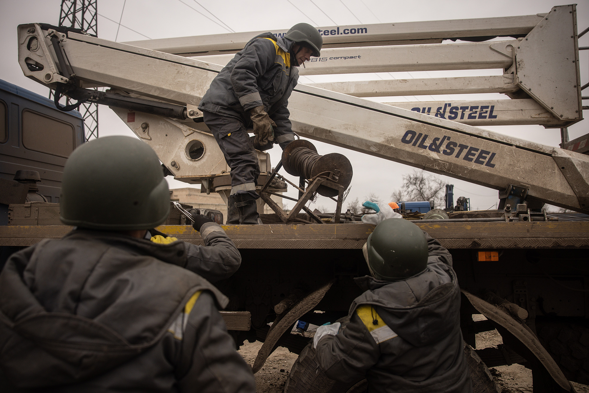 Electricity workers wearing bulletproof vests and helmets prepare to start work to repair a destroyed high voltage power line on December 1, in Kherson, Ukraine.