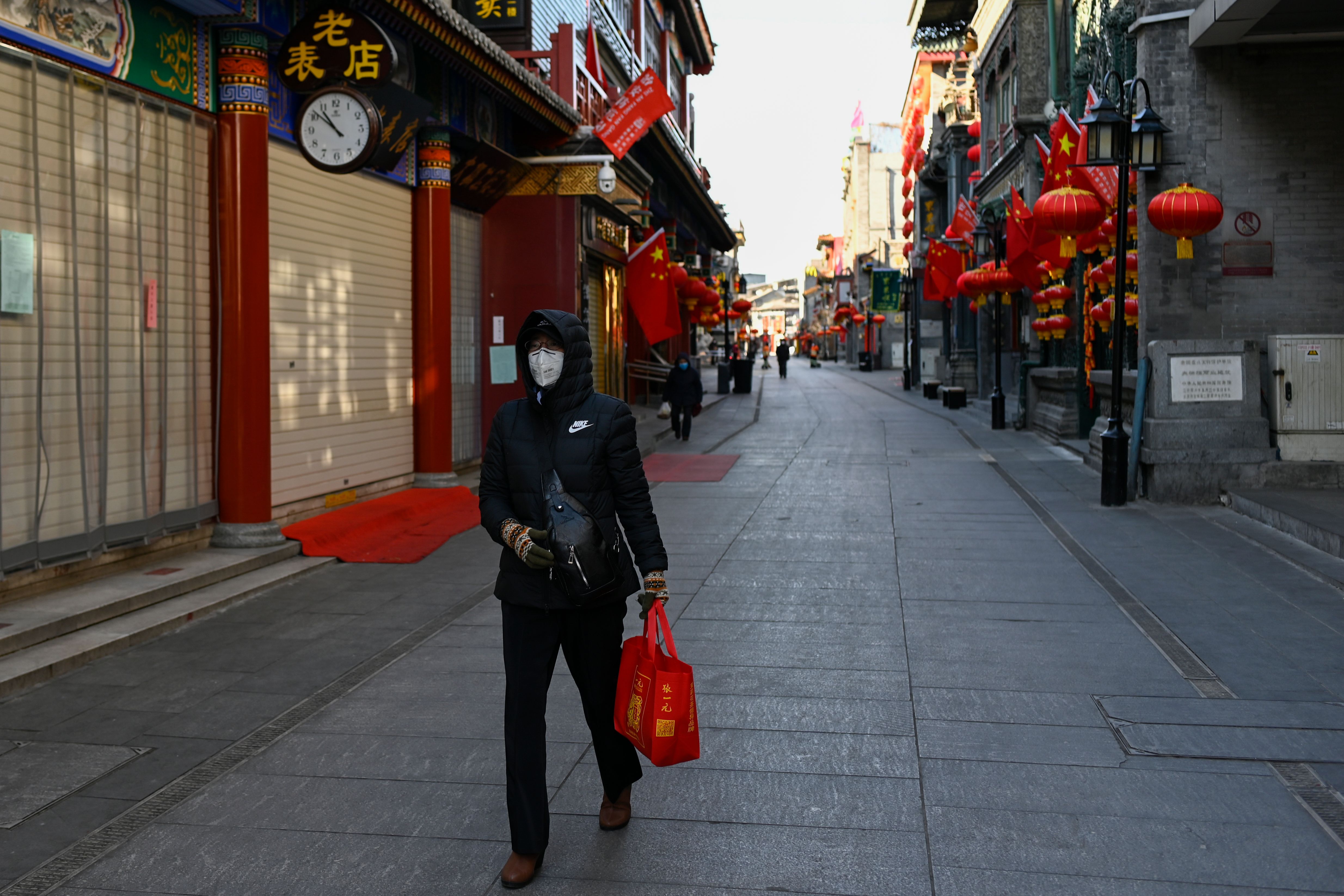 A woman walks along a shuttered business street in Beijing on February 4.