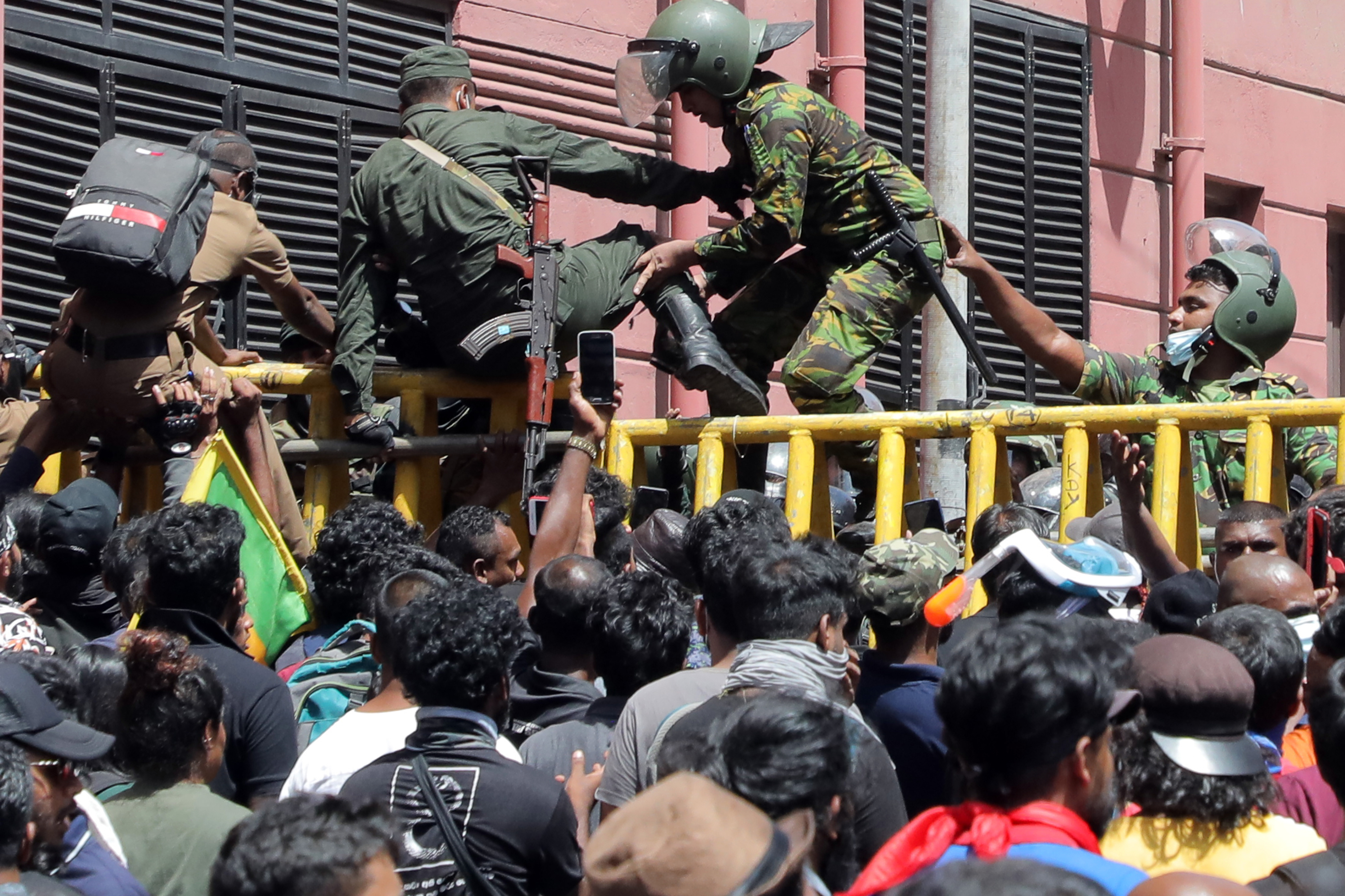 Soldiers and Police Special Task Force personnel jump across steel barriers as protesters attempt to push them down near the road that leads to the presidential residence in Colombo, Sri Lanka, on July 9. 