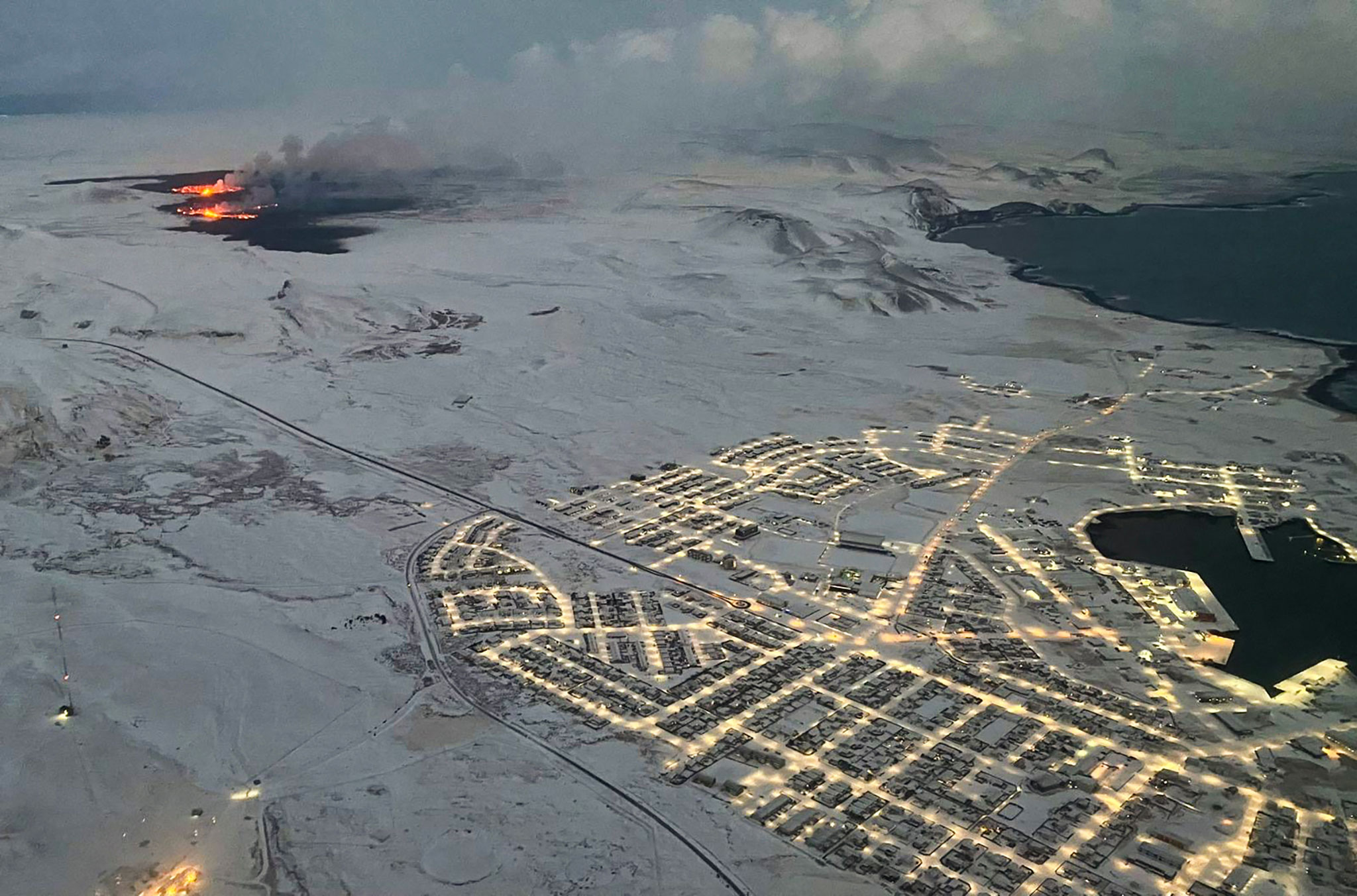 The evacuated Icelandic town of Grindavik is seen as smoke billows and lava is thrown into the air from a fissure on Tuesday.