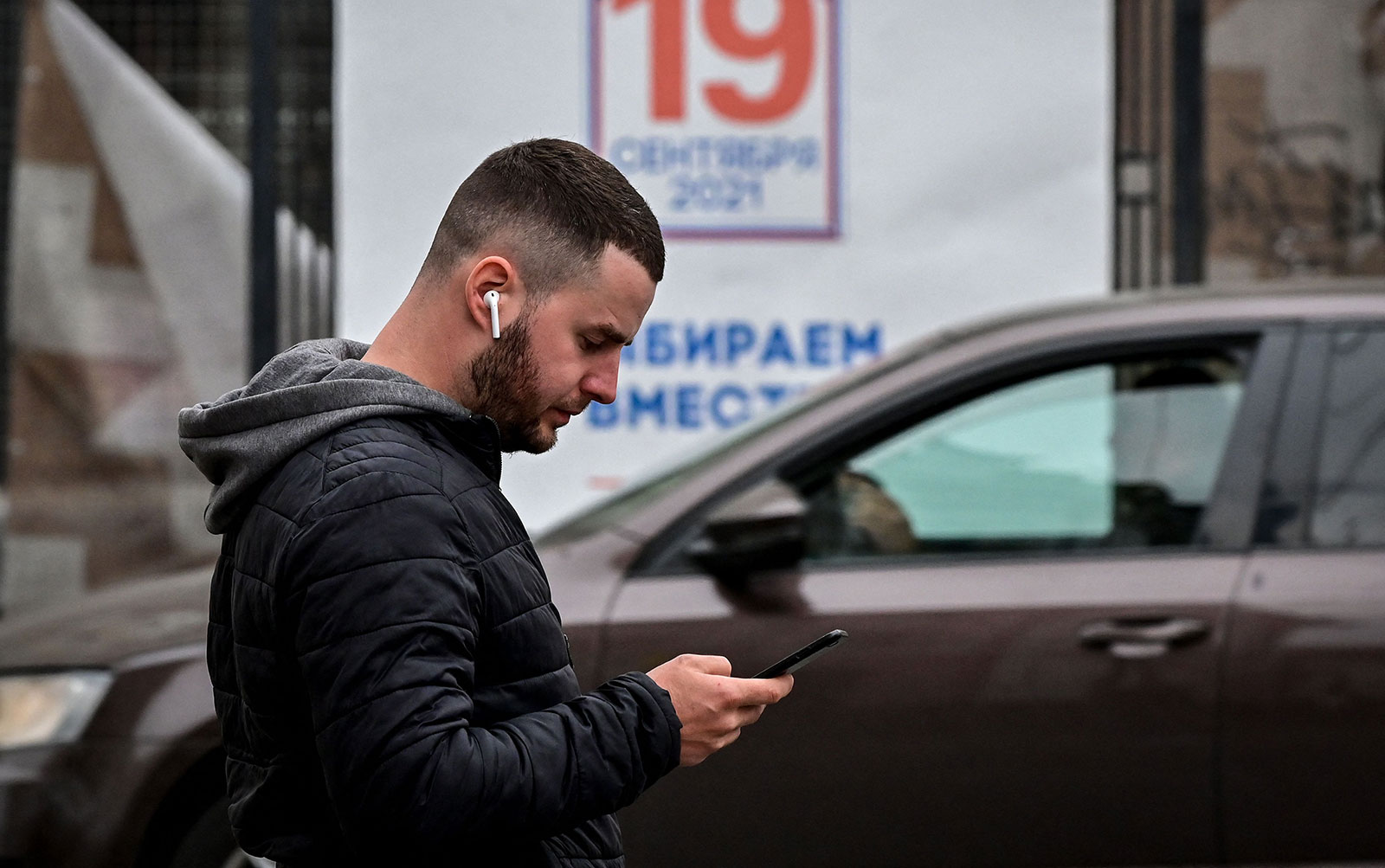 A man checks his phone while walking down a street in Moscow in 2021.