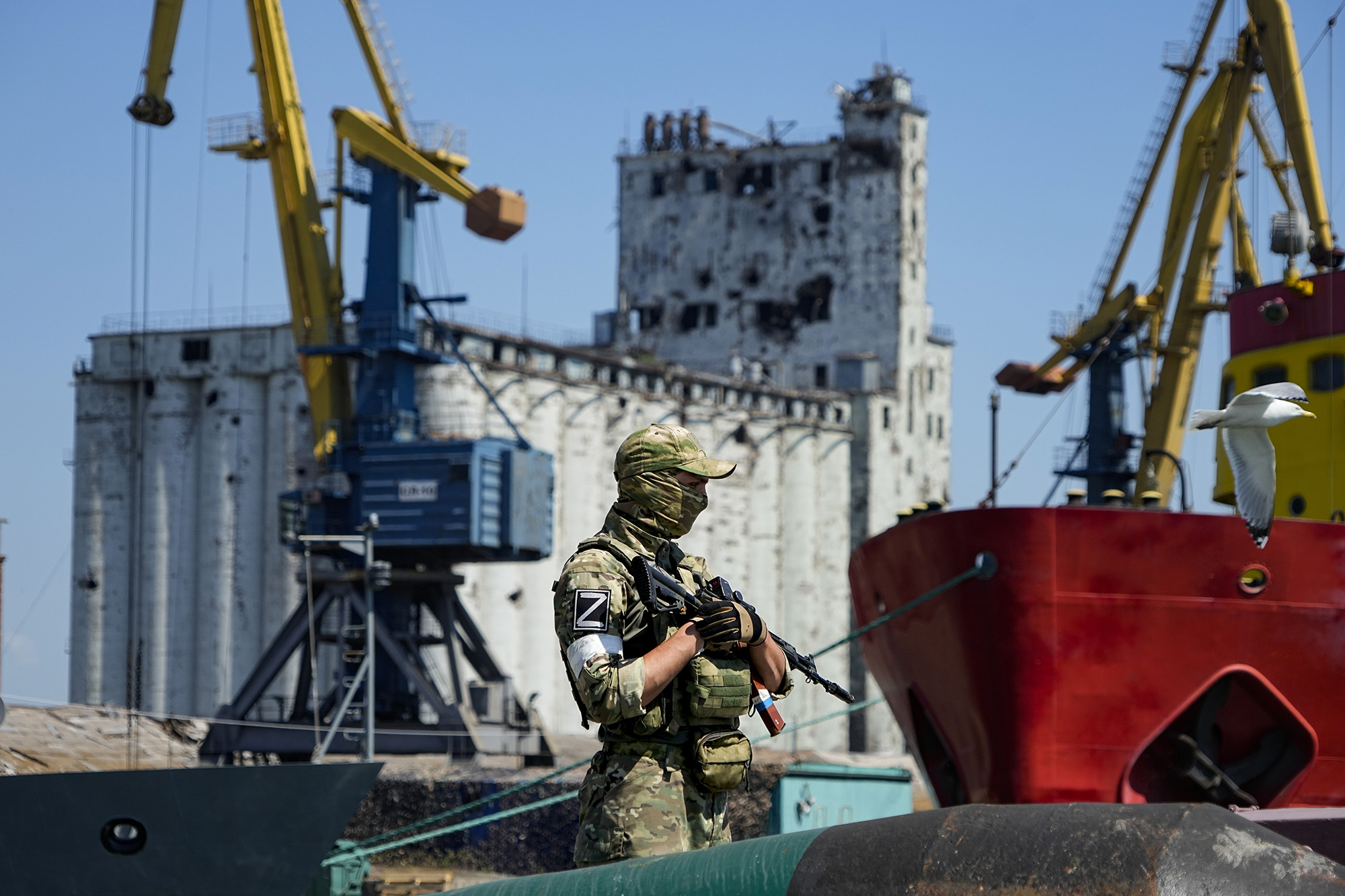 A Russian soldier guards a pier with grain storage silos in the background at Mariupol Sea Port, Ukraine, on June 12.