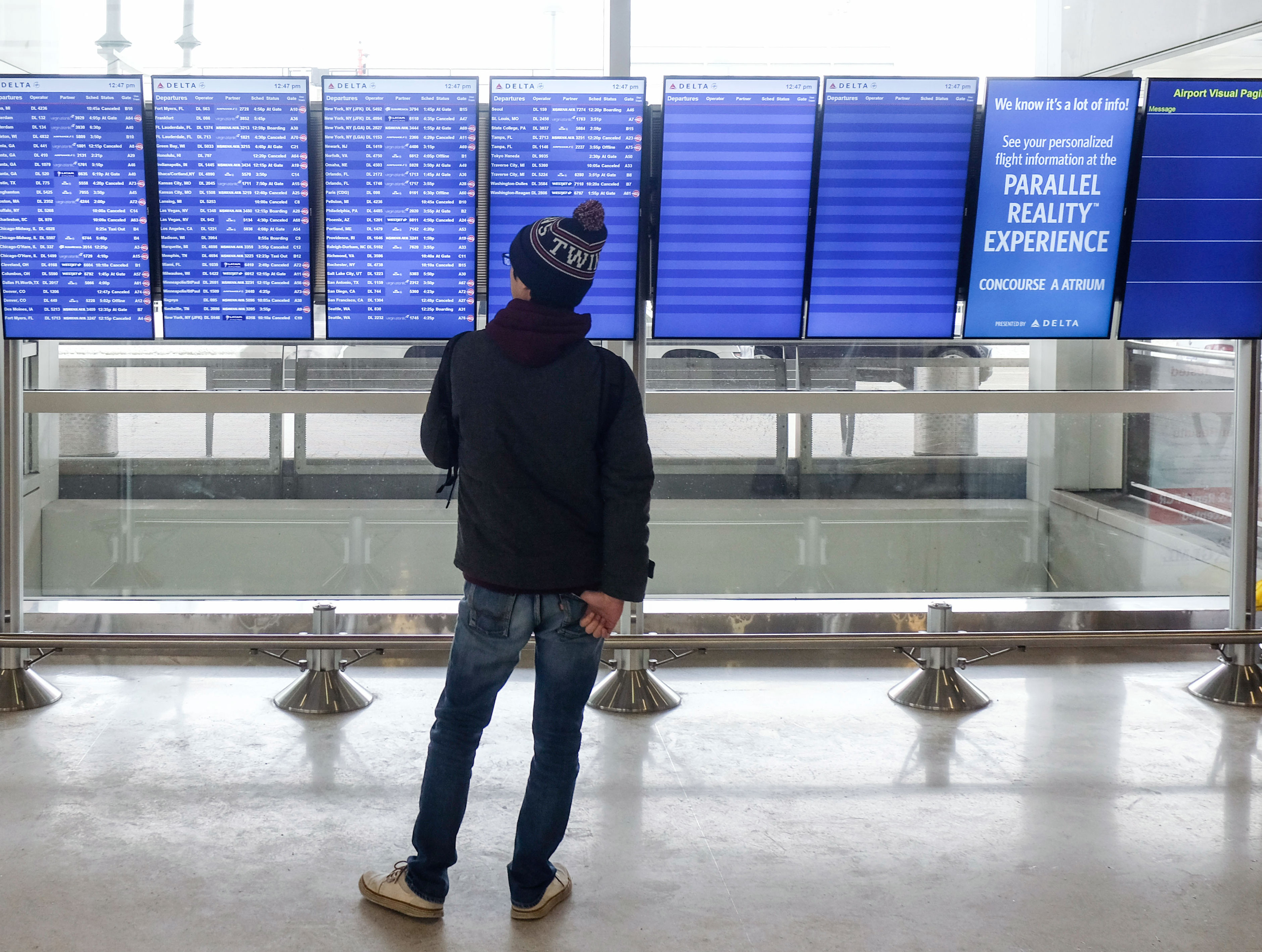 A traveler checks a message board showing flight cancellations and delays at Detroit's Wayne County Metropolitan Airport on Saturday. 