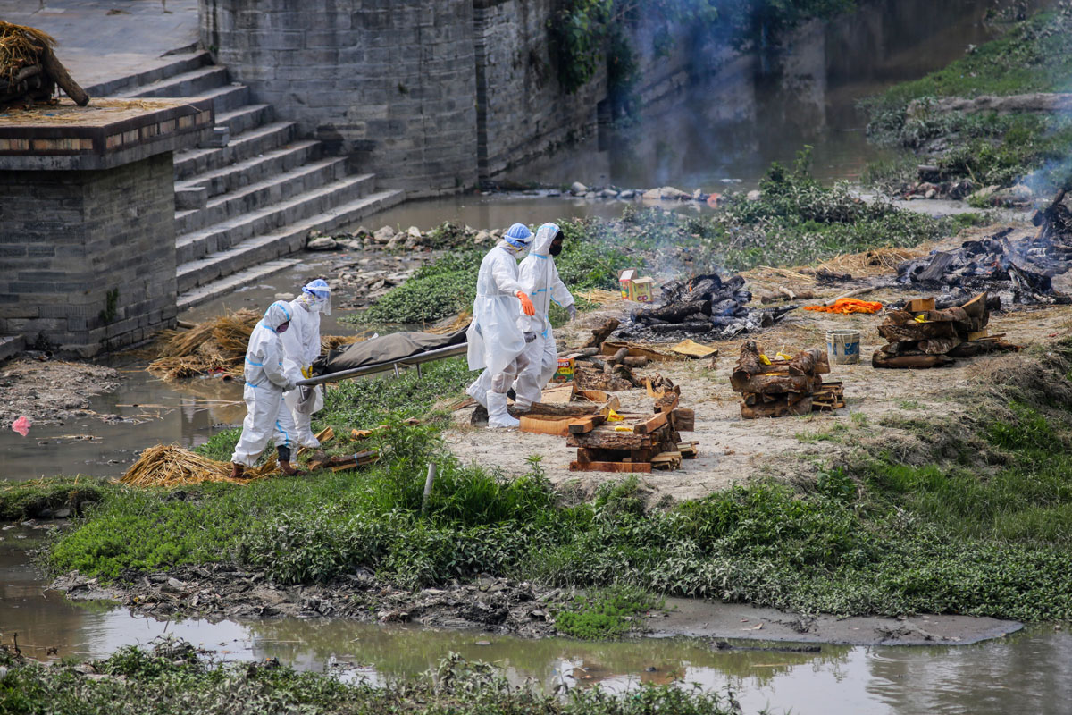 Men wearing personal protective equipment carry the body of a Covid-19 victim to cremate on the bank of Bagmati River in Kathmandu, Nepal on May 3.