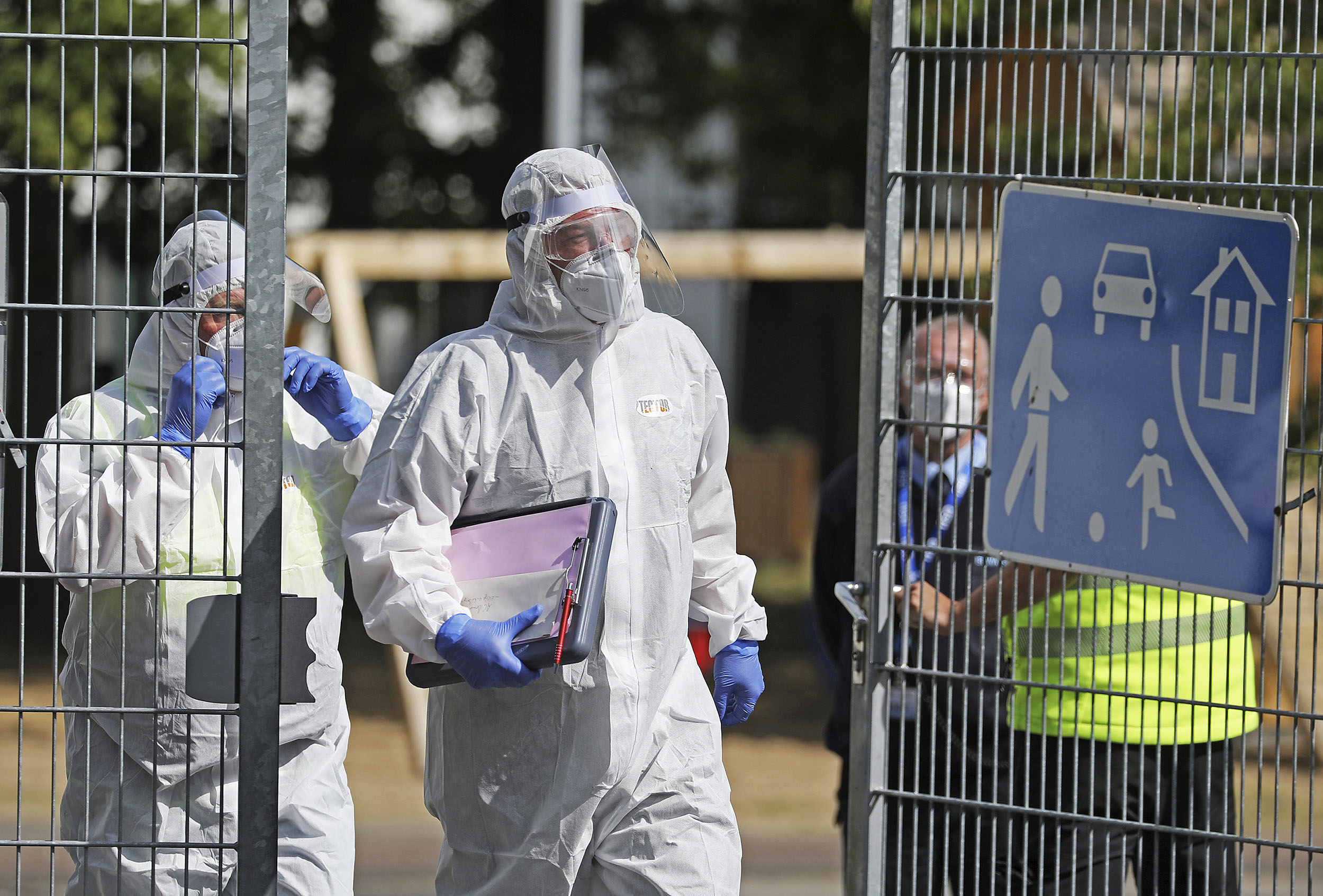 Employees of the Public Order Office in protective suits leave a refugee accommodation in Sankt Augustin, Germany, on Monday 18. 