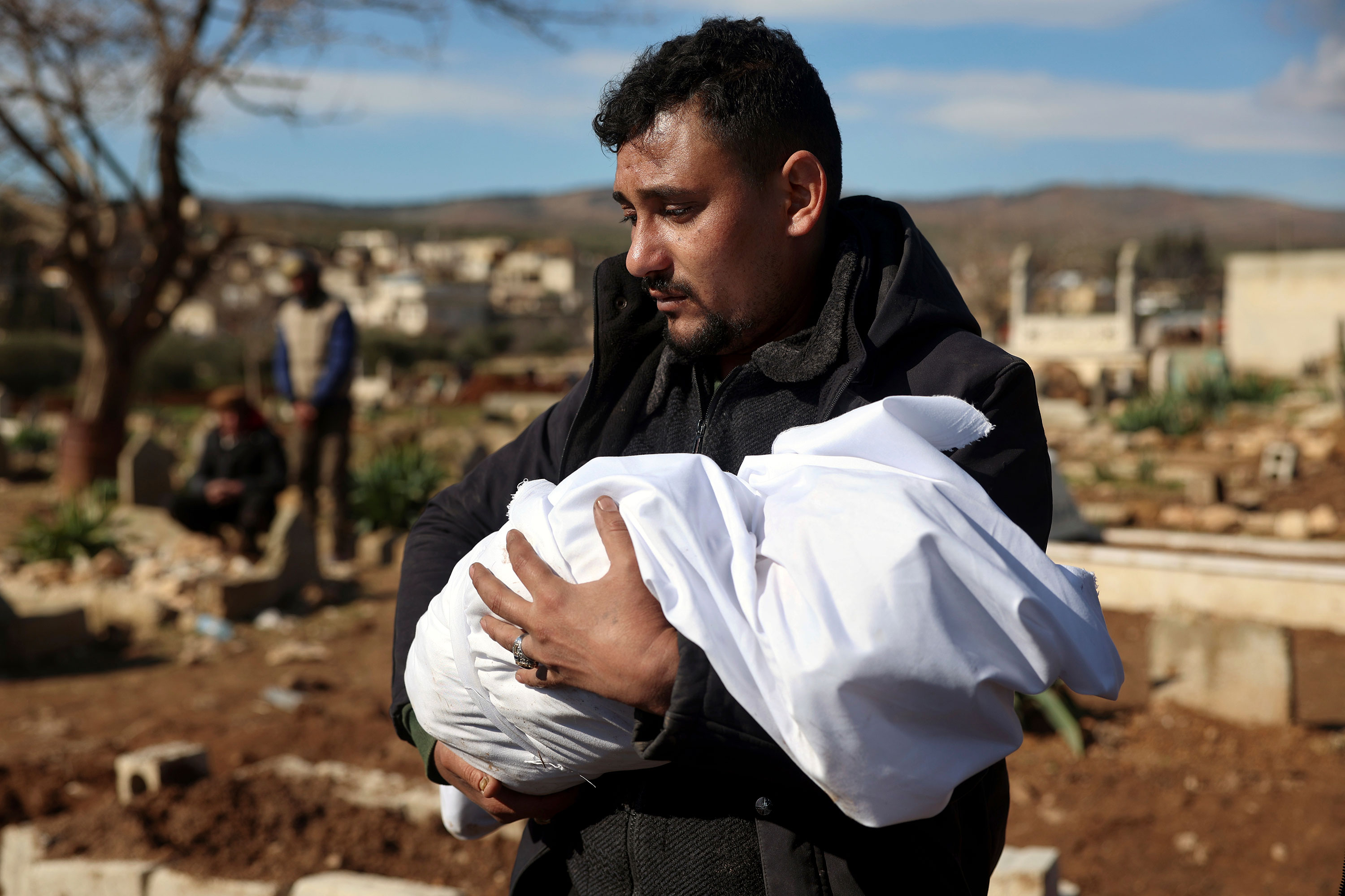 A man carries the body of one of the baby's family members for burial on Tuesday.