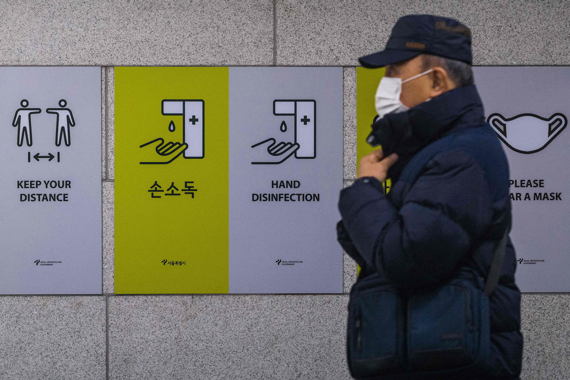 Un banlieusard passe devant des panneaux d'information affichés pour rappeler au public comment aider à prévenir la propagation du coronavirus Covid-19 à Séoul le 1er décembre 2021.
