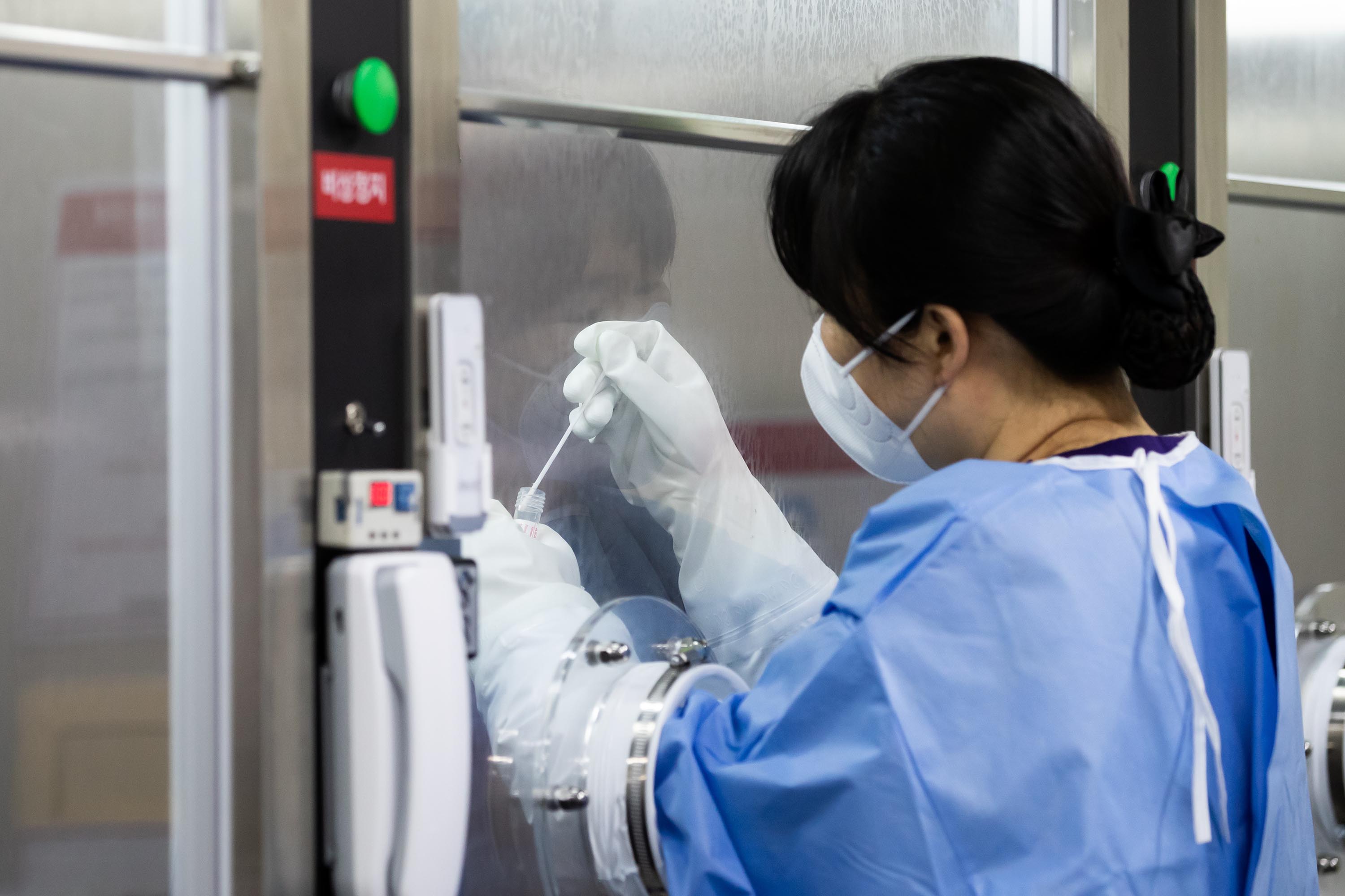 A medical worker collects a sample from a visitor at a hospital's walk-thru testing center in Seoul, South Korea, on Friday, July 24.