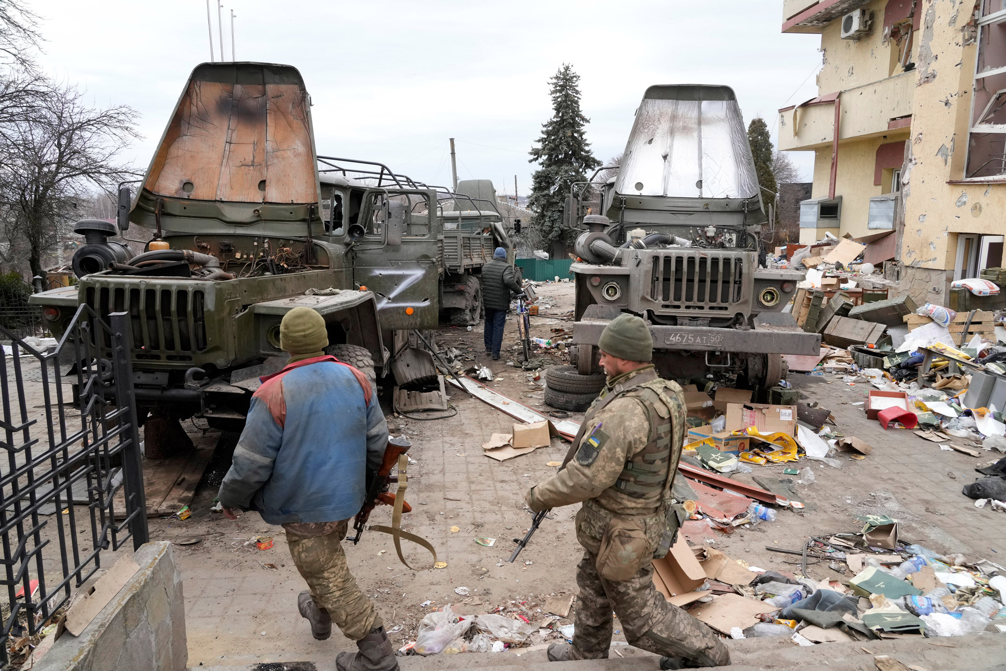 Ukrainian soldiers walk near damaged Russian military trucks in the town of Trostsyanets, Ukraine on March 28.