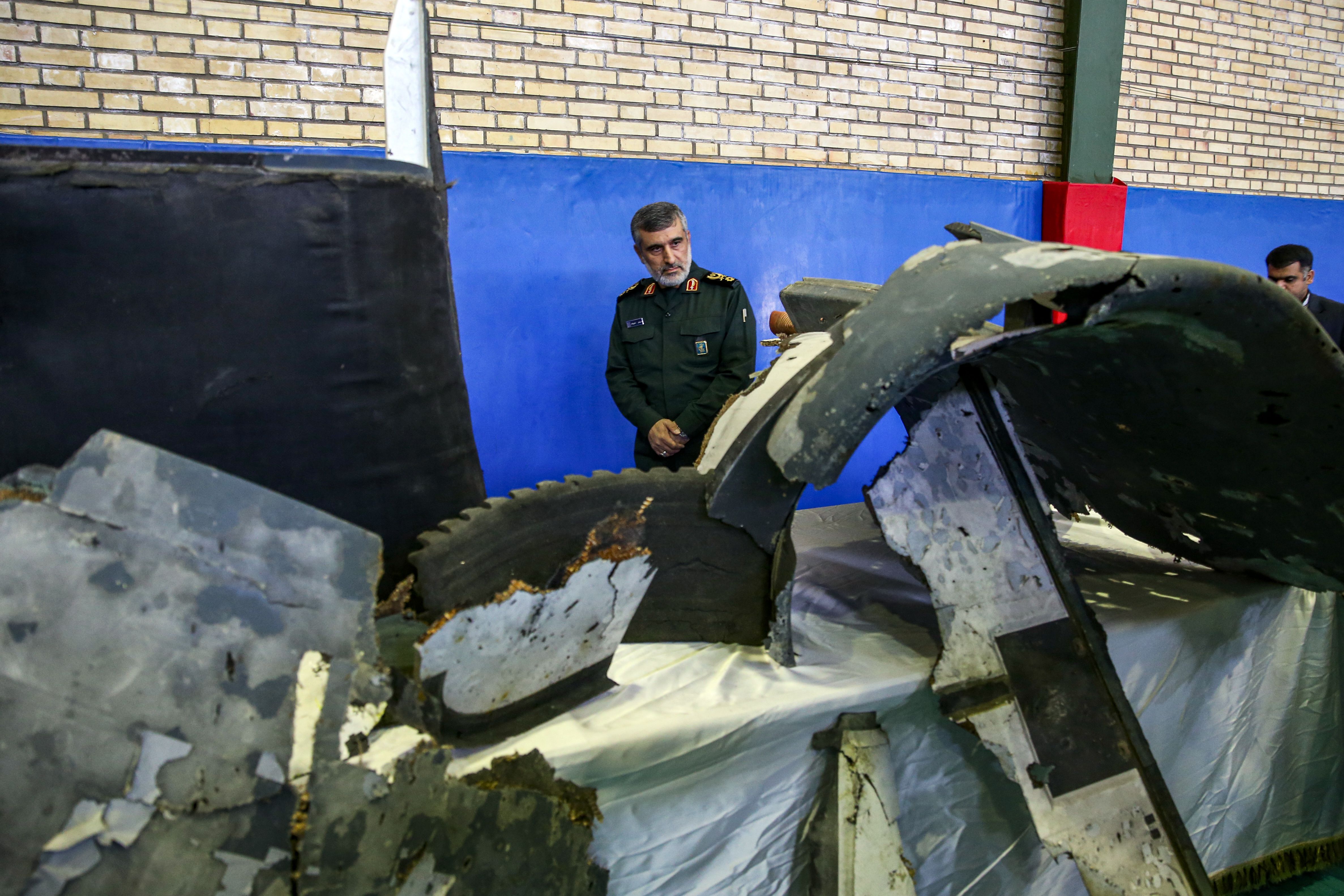 General Amir Ali Hajizadeh (C), Iran's Head of the Revolutionary Guard's aerospace division, looks at debris from a downed US drone reportedly recovered within Iran's territorial waters and put on display by the Revolutionary Guard in the capital Tehran on June 21, 2019.