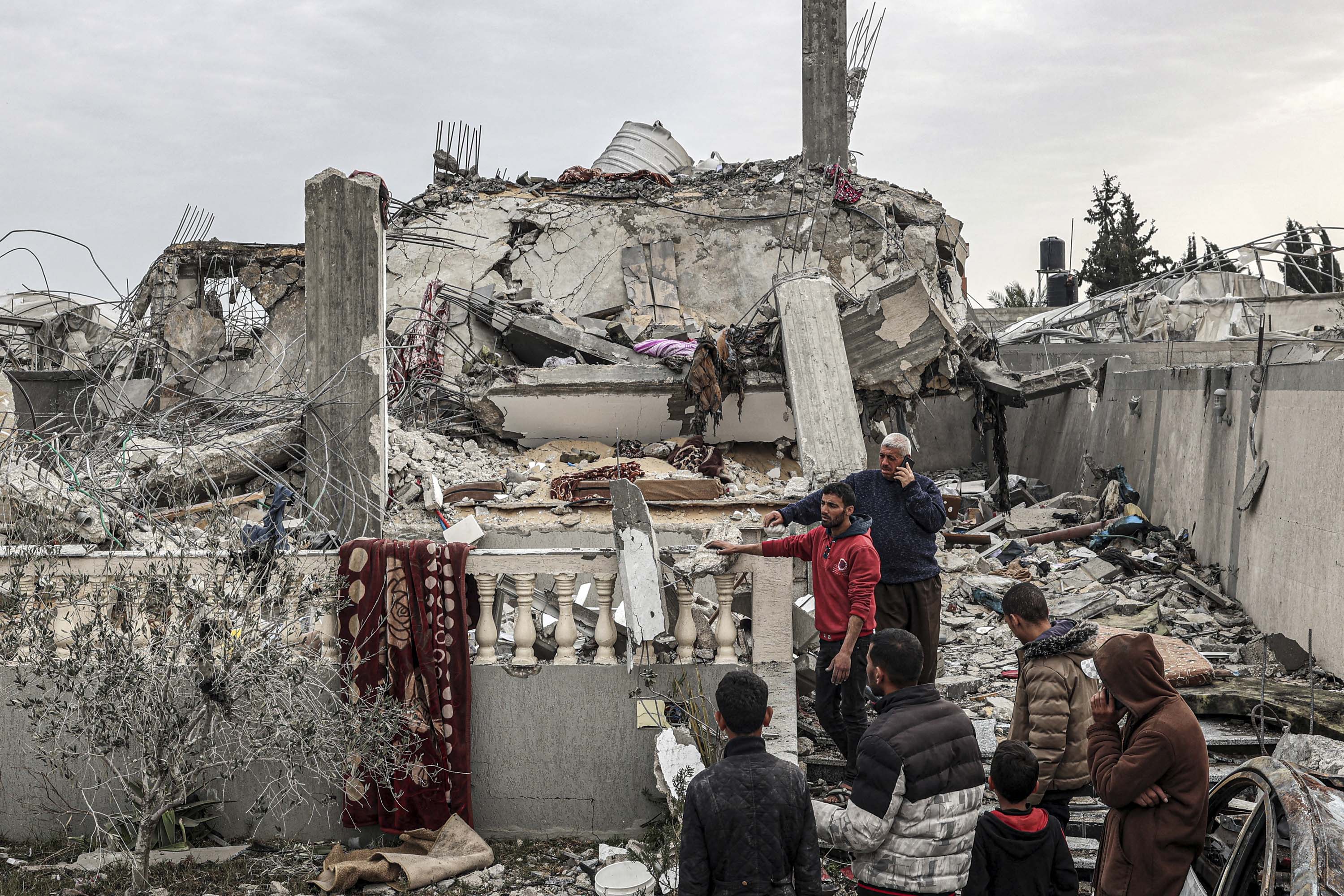 People inspect damage to a building that was struck during Israeli bombardment the previous night in Rafah, on March 26. 