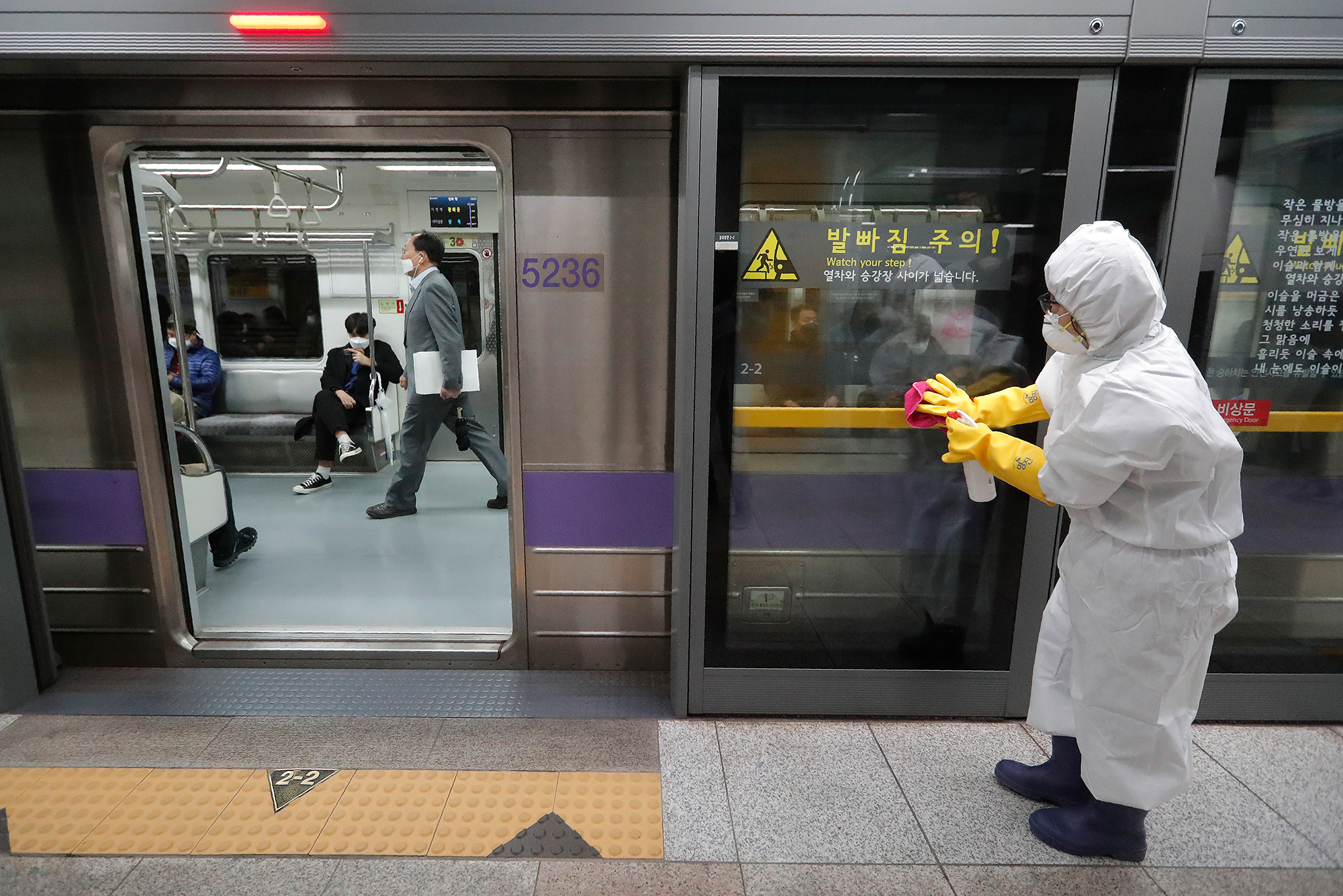 A worker wearing protective gears disinfects a door as a precaution against the new coronavirus at a subway station in Seoul, South Korea, Friday, February 28.