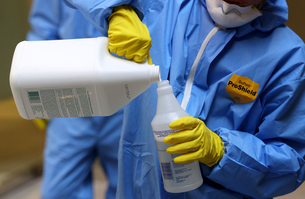 A Maryland Cleaning and Abatement Services employee prepares a Virucidal disinfectant before preforming a preventative fogging and damp wipe treatment at an office building on March 21 in Hunt Valley, Maryland.