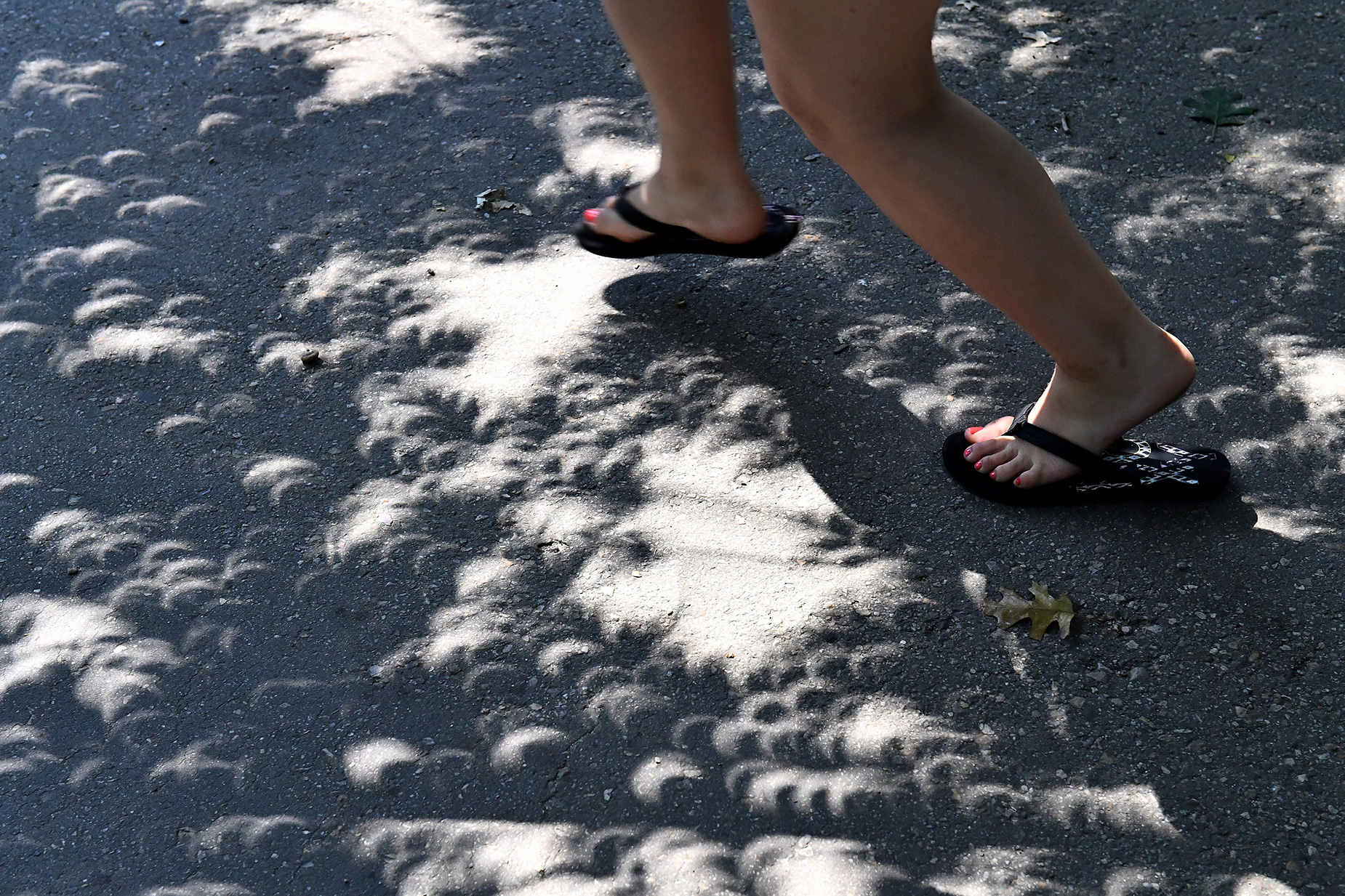 A spectator runs through crescent shaped shadows created by the solar eclipse in Washington, DC, on August 21, 2017.