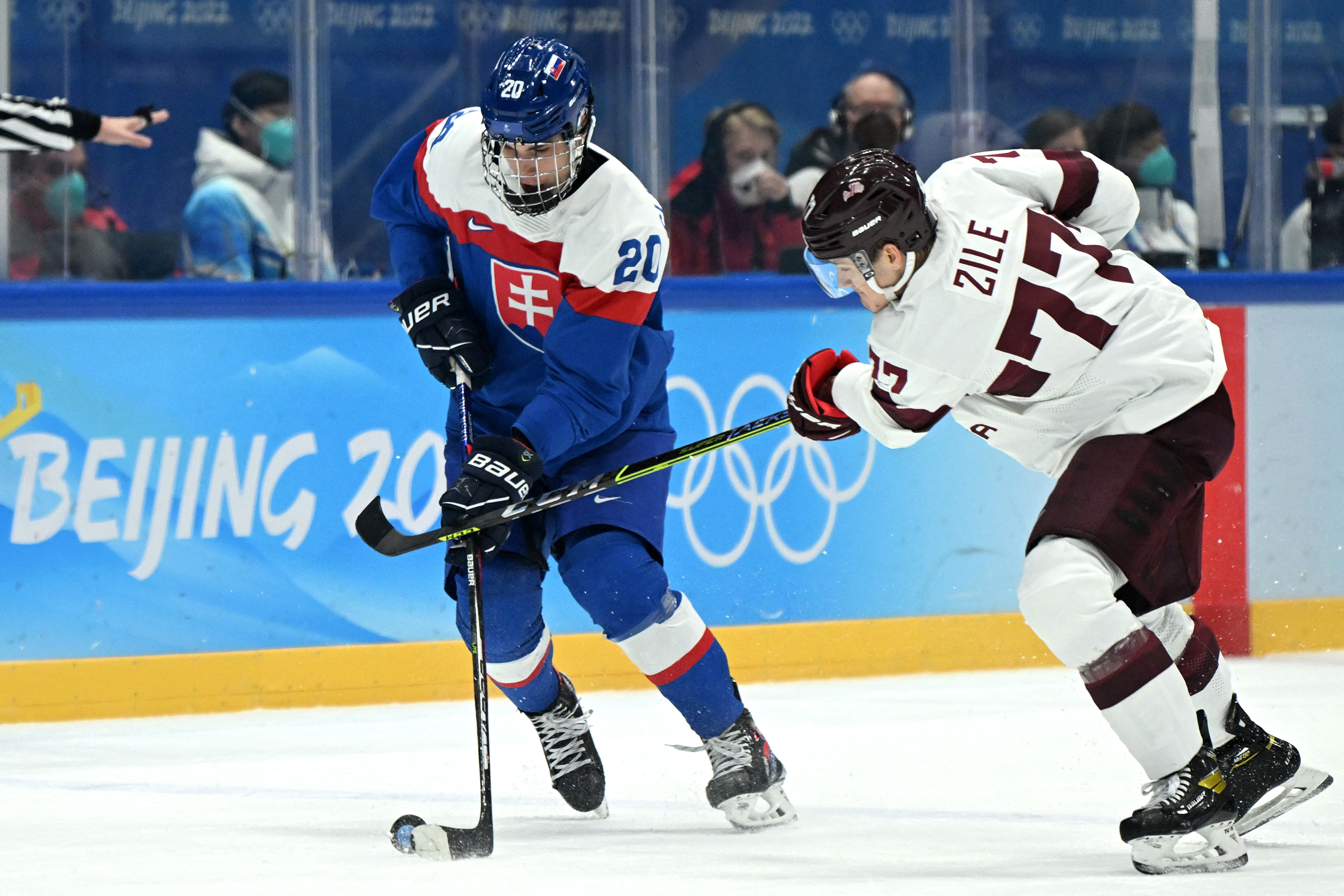 Slovakia's Juraj Slafkovský, left, and Latvia's Kristaps Roberts Zile fight for the puck during the men's preliminary round group C ice hockey competition on February 13.