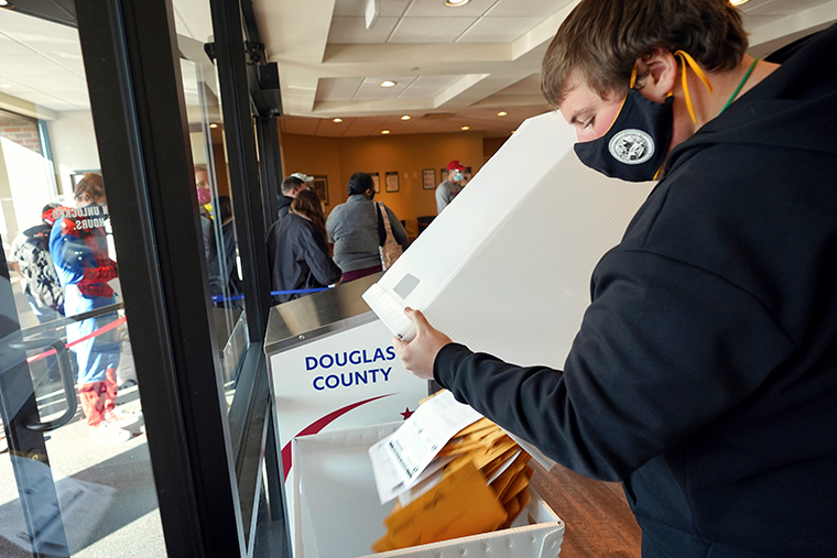 A Douglas County Election Commission worker collects early ballots from a ballot drop box at the Commission offices in Omaha, Neb., Saturday, Oct. 31, 2020. 