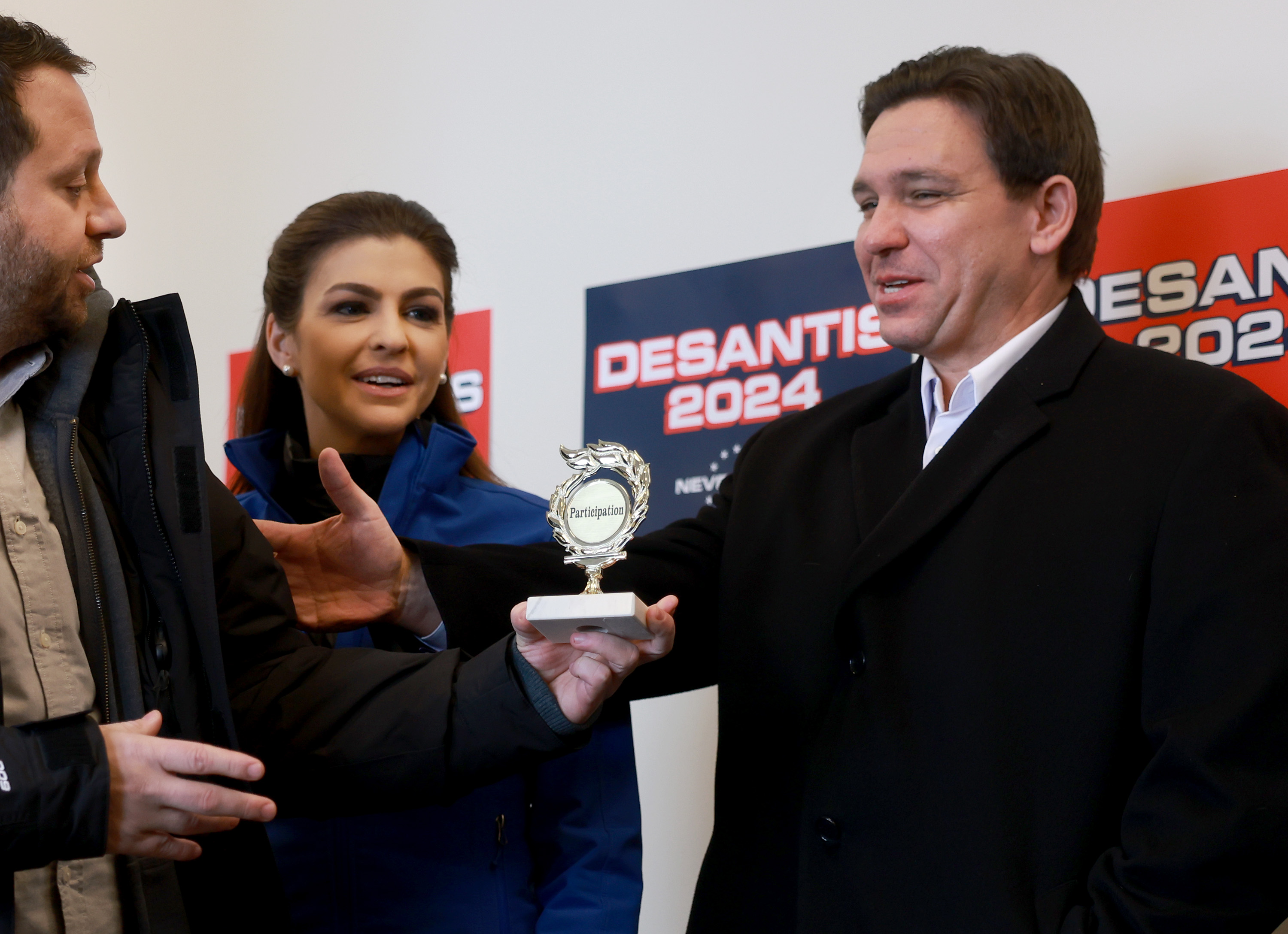 A person tries to give Florida Gov. Ron DeSantis a participation trophy during a campaign stop in Atlantic, Iowa, on January 13.