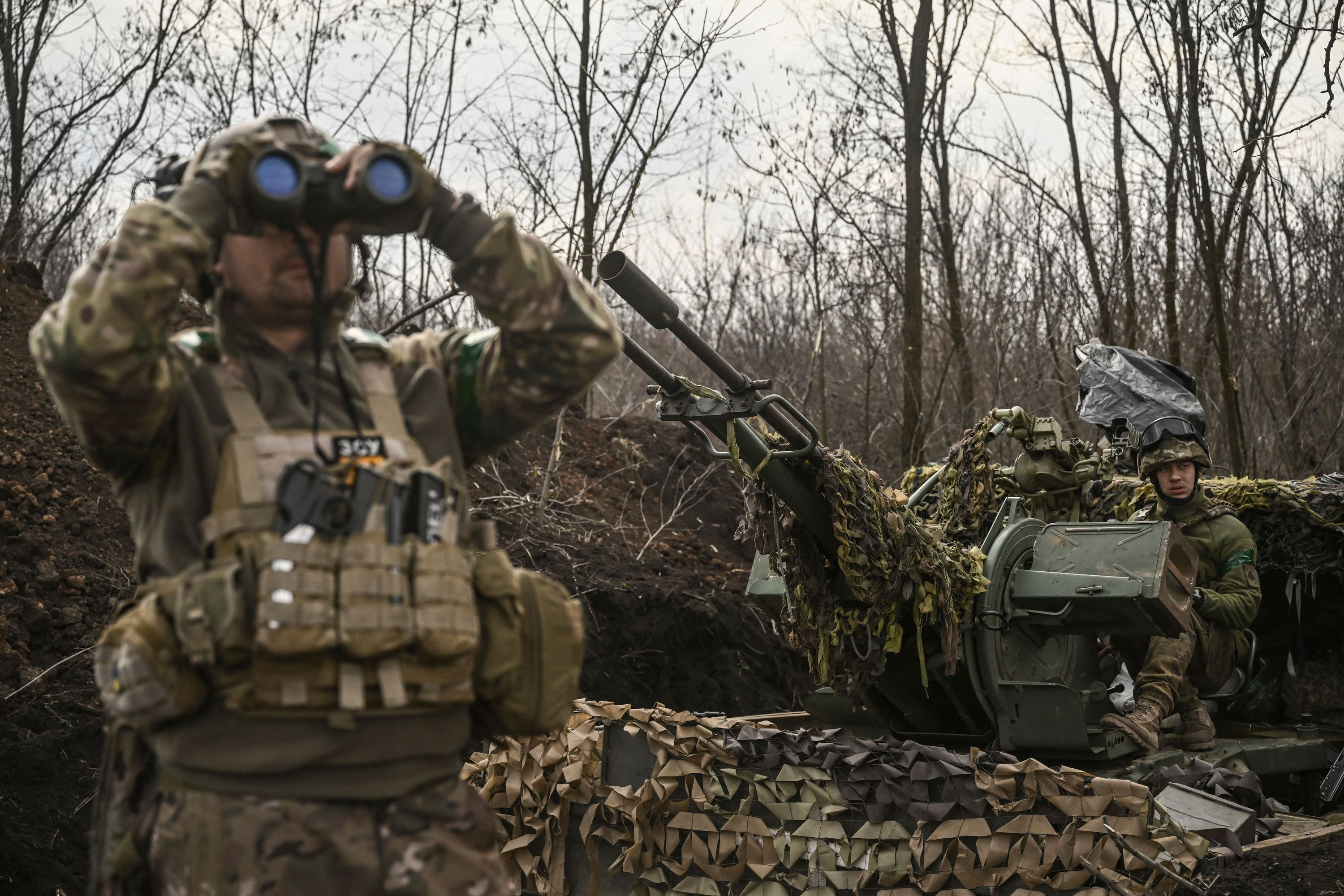 A Ukrainian serviceman looks through goggles while another sits on an anti-air gun near Bakhmut on March 24. 