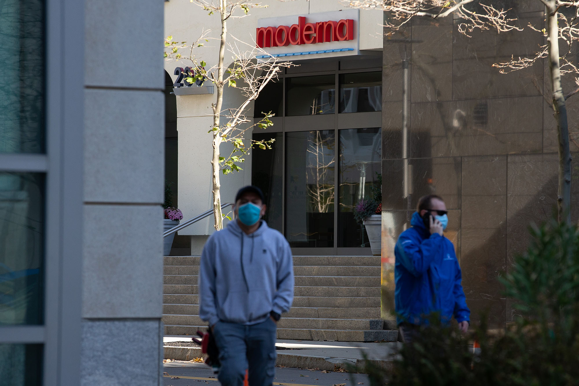 Pedestrians wearing face masks walk past the headquarters of biotechnology company Moderna in Cambridge, Massachusetts on November 16. 