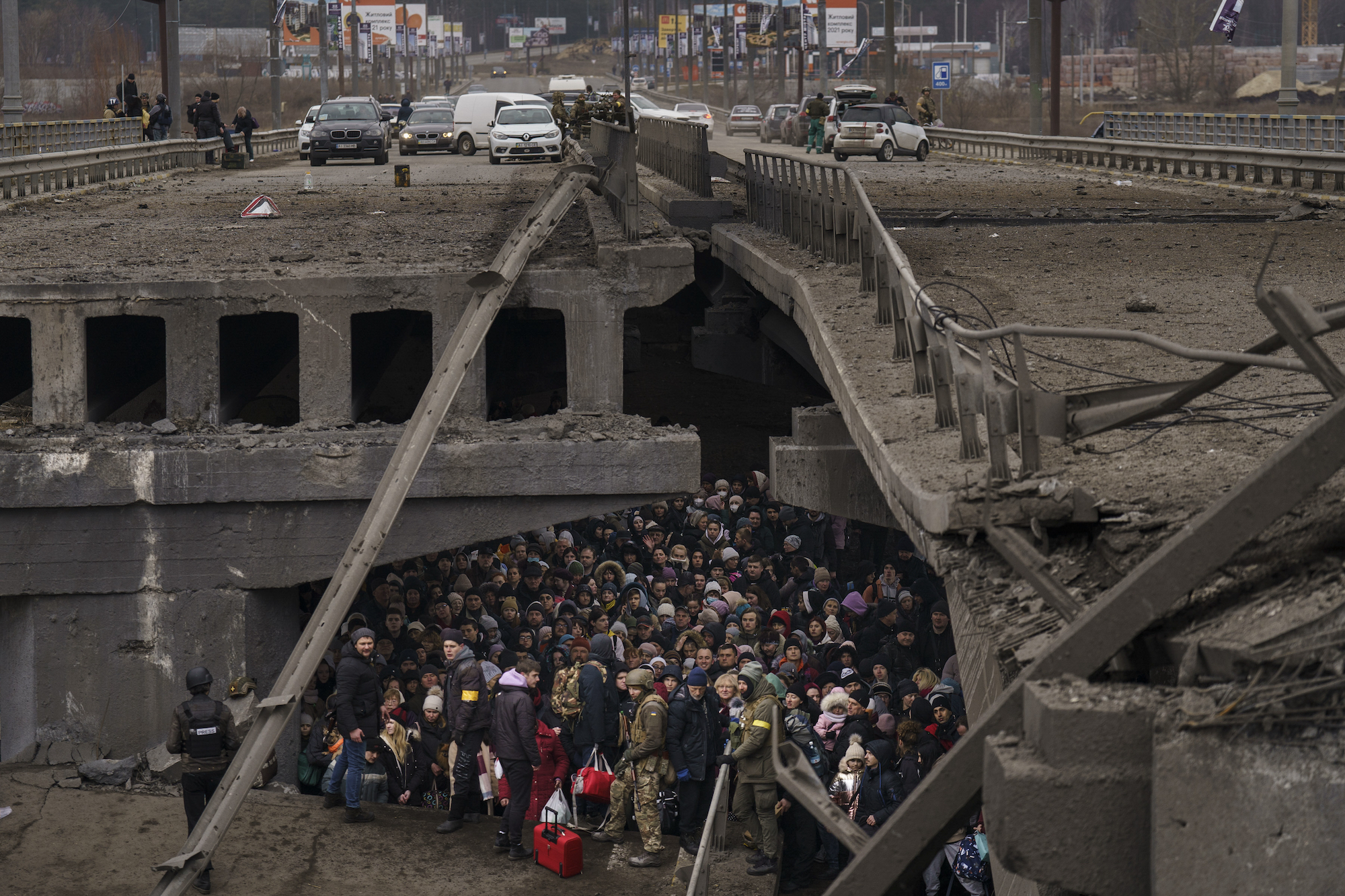 People crowd under a destroyed bridge as they try to flee by crossing the Irpin River on the outskirts of Kyiv on March 5, 2022.