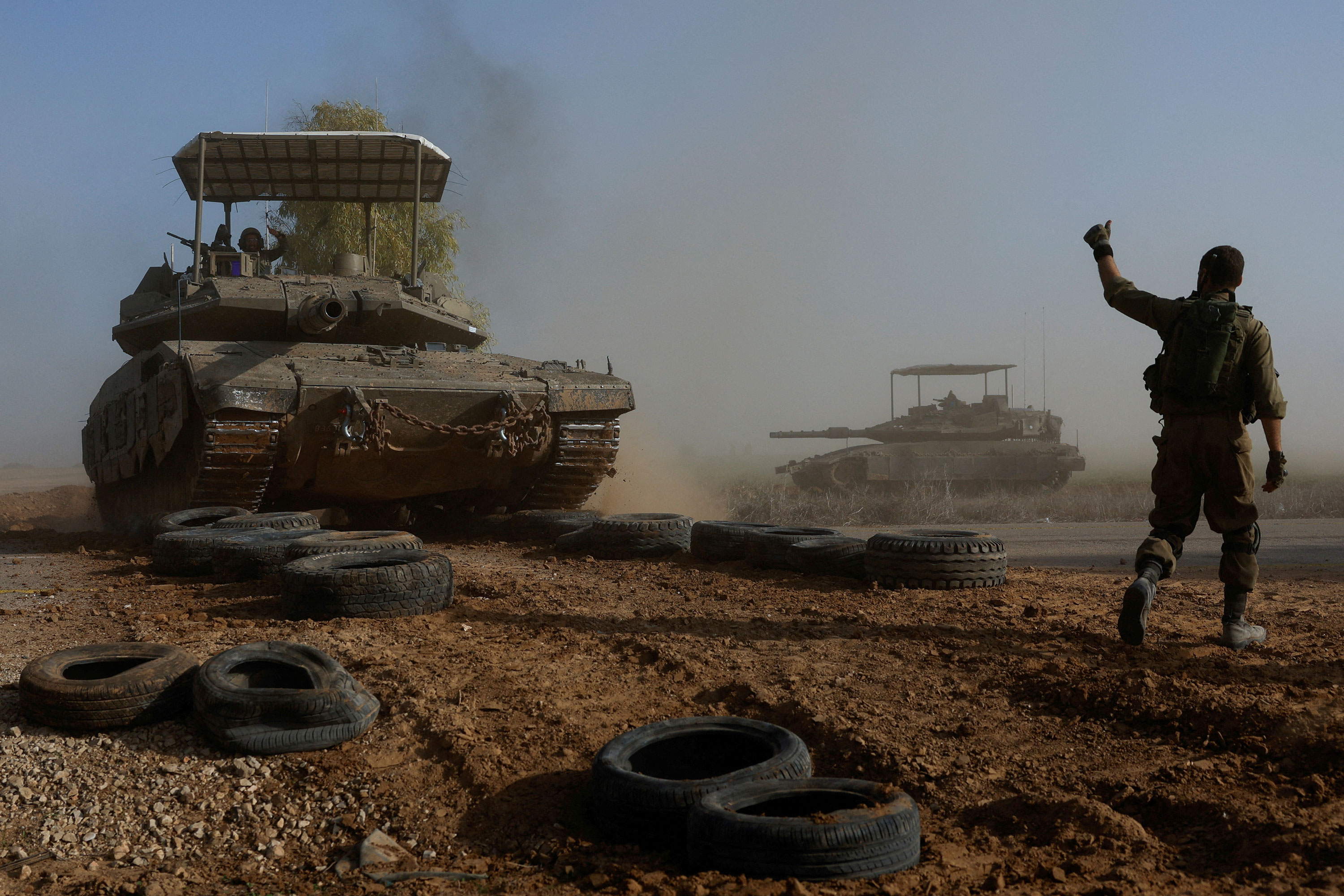 An Israeli soldier gestures toward a tank crew traveling as part of a convoy near Israel's border with southern Gaza on Monday.