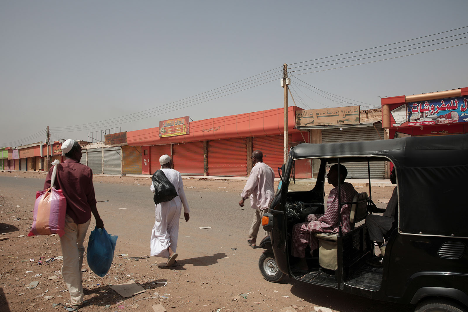 People walk past shuttered shops in Khartoum, Sudan, on Monday, April 17.