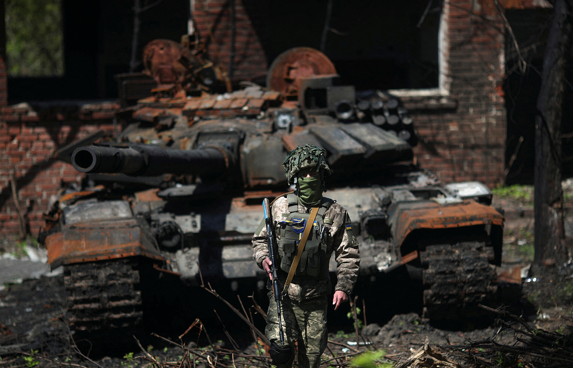 A Ukrainian soldier stands next to a destroyed Russian tank in Malaya Rohan village near Kharkiv, Ukraine, on May 5.