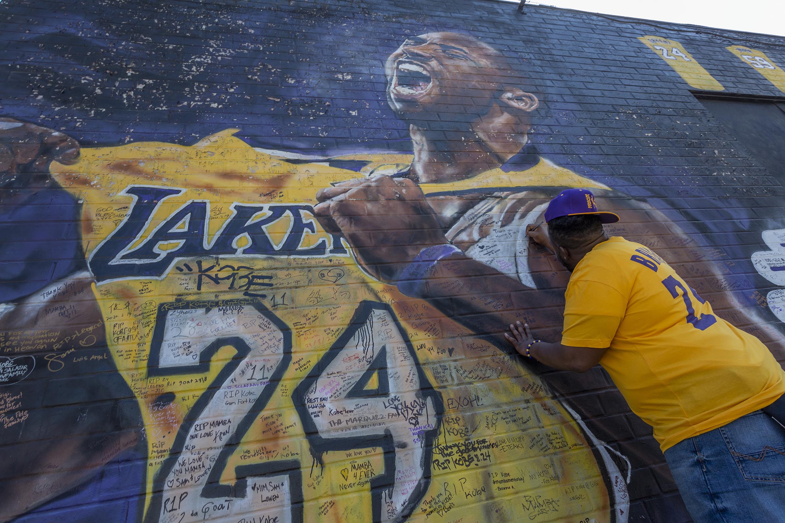A fan writes a message on a mural for former Los Angeles Lakers basketball star Kobe Bryant for him and his daughter, Gianna, at nearby Staple Center in Los Angeles, on February 24. 