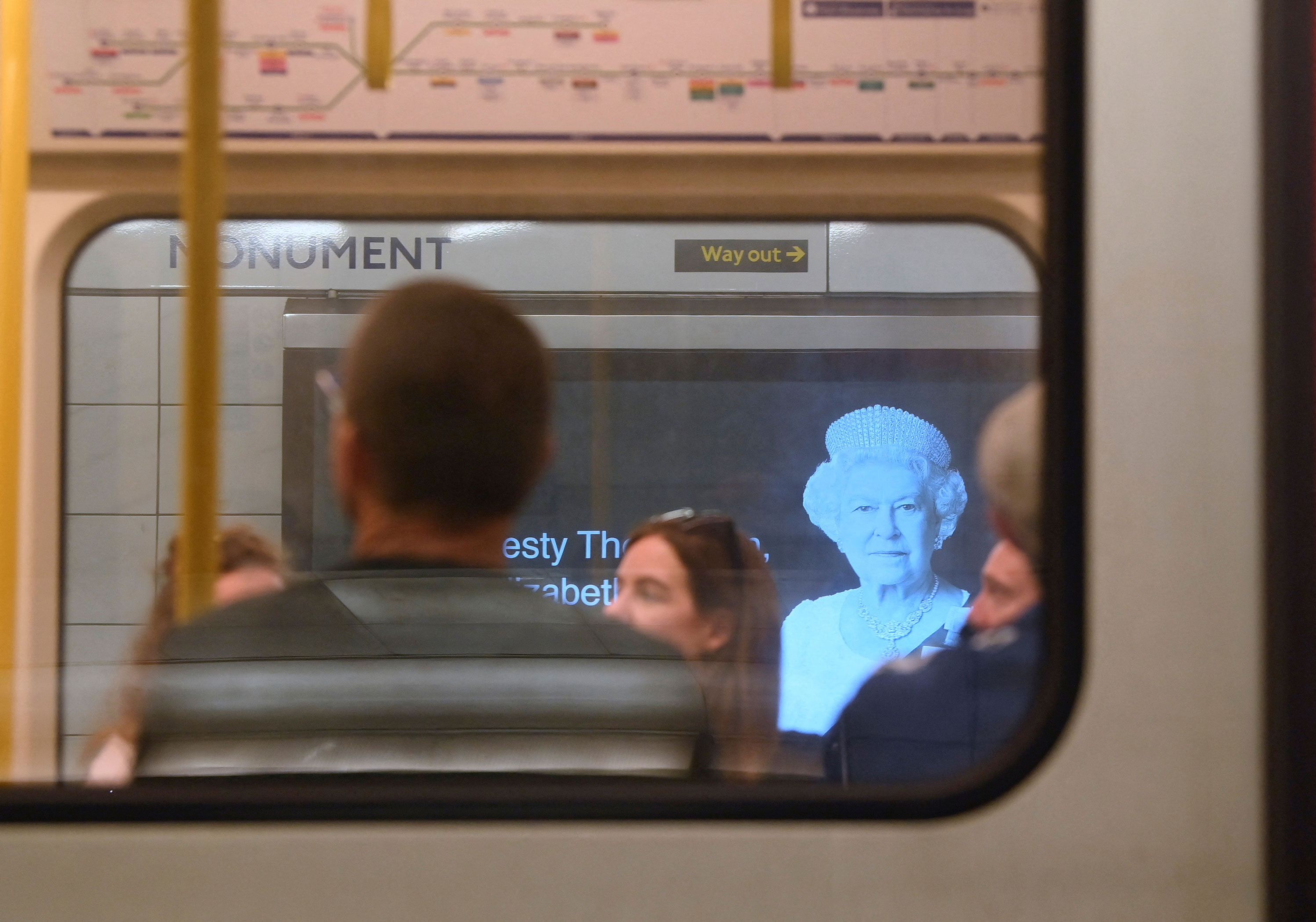London Underground train passengers pass a billboard image of Queen Elizabeth in London on September 10.