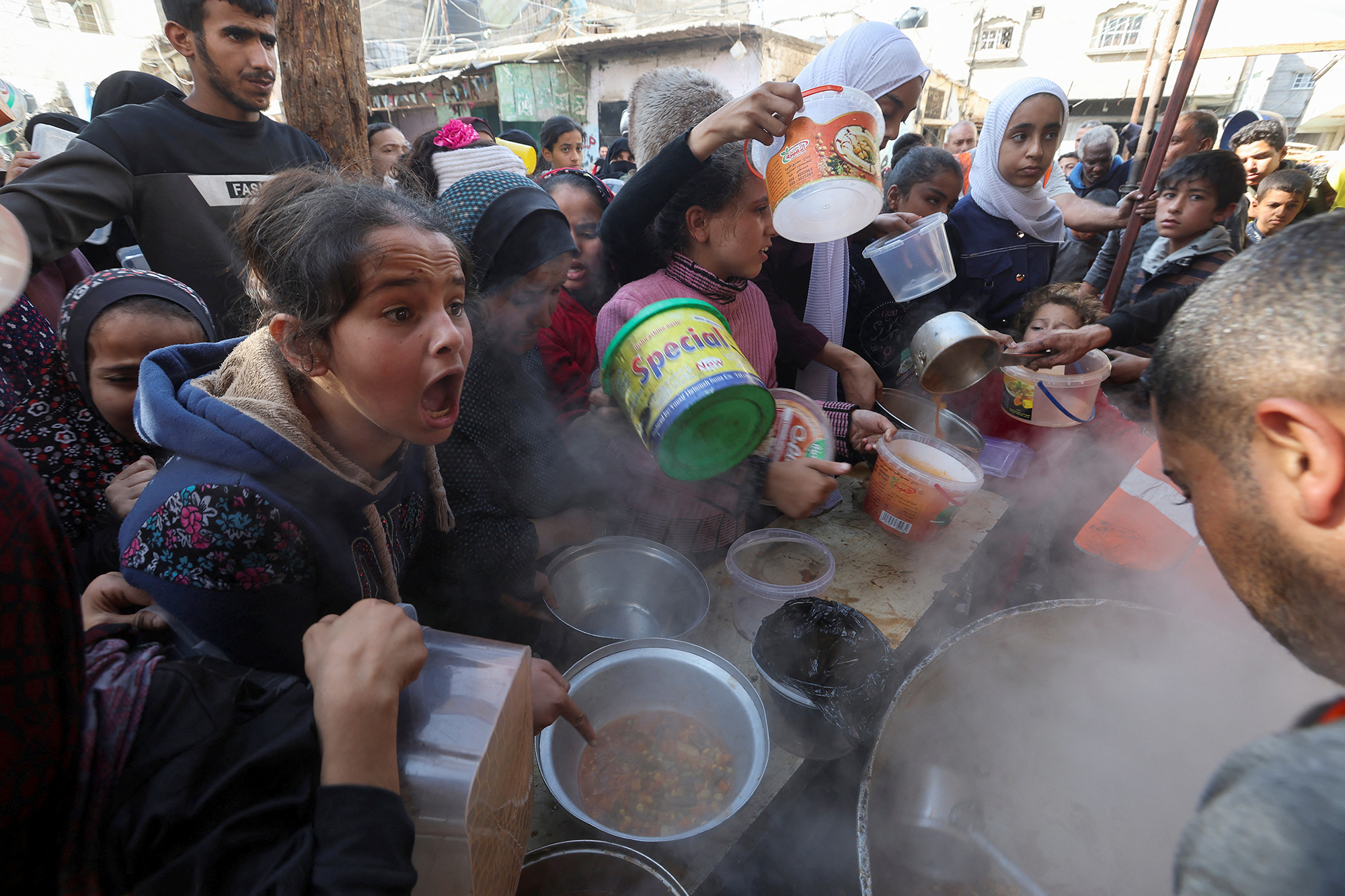 A Palestinian child reacts while people gather to get their share of charity food offered by volunteers amid food shortages in Rafah, Gaza, on December 2.
