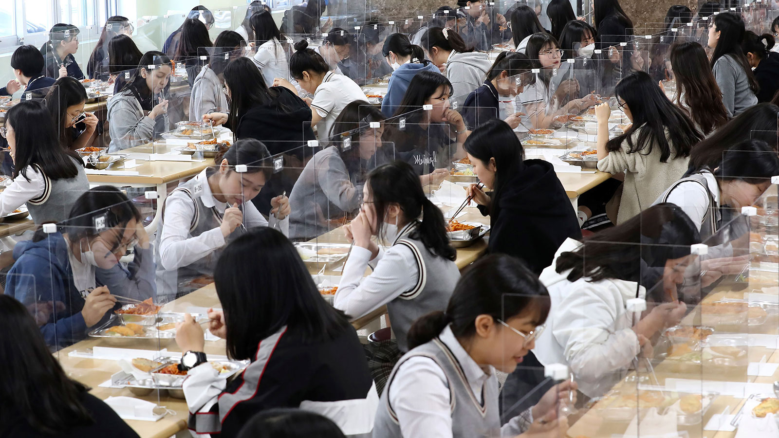 Senior students eat lunch at tables equipped with plastic barriers to prevent possible spread of the novel coronavirus in the cafeteria at Jeonmin High School in Daejeon, South Korea on May 20.
