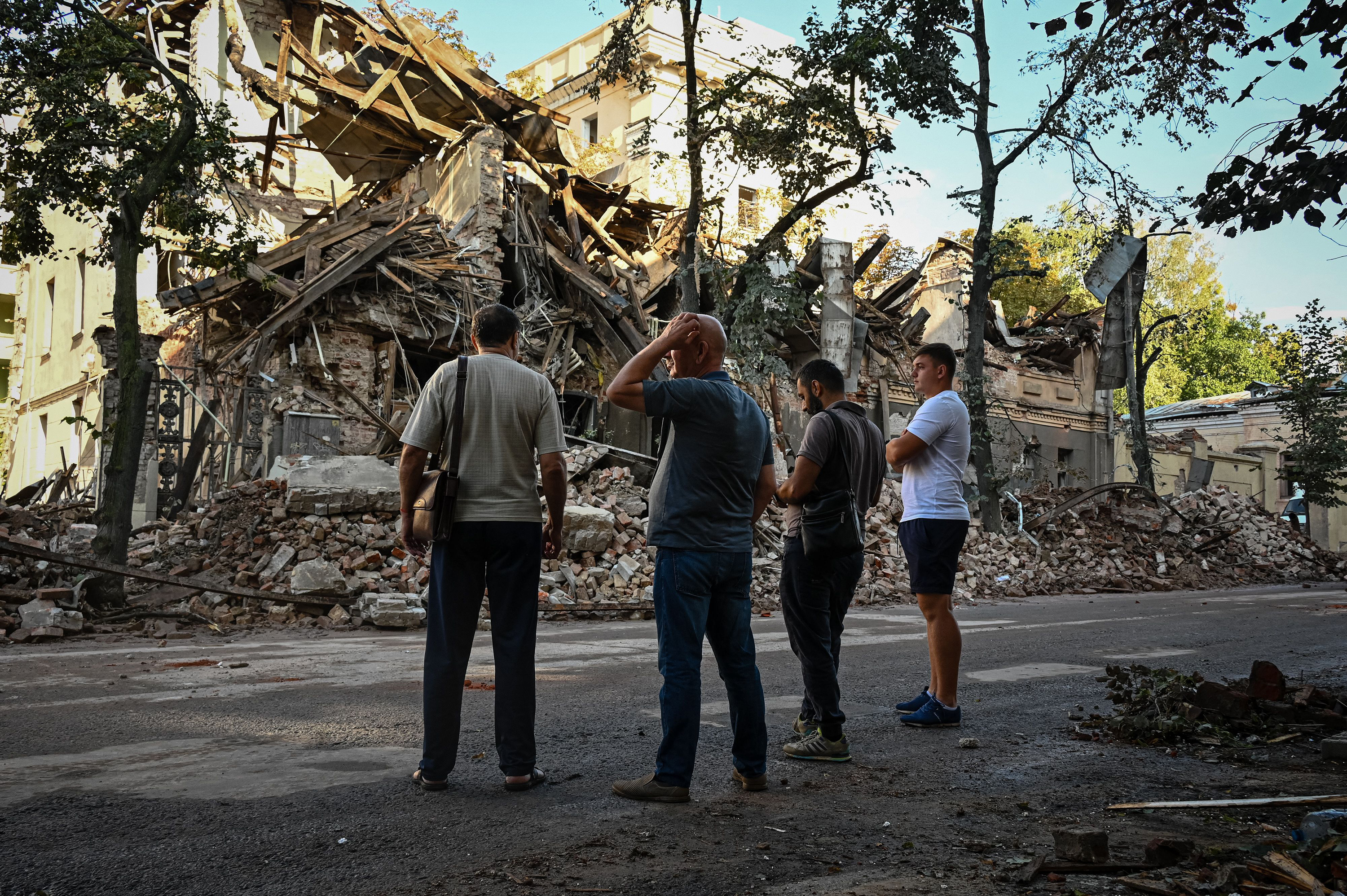 People stand near a destroyed building following a missile strike in Kharkiv, Ukraine on August 29. 