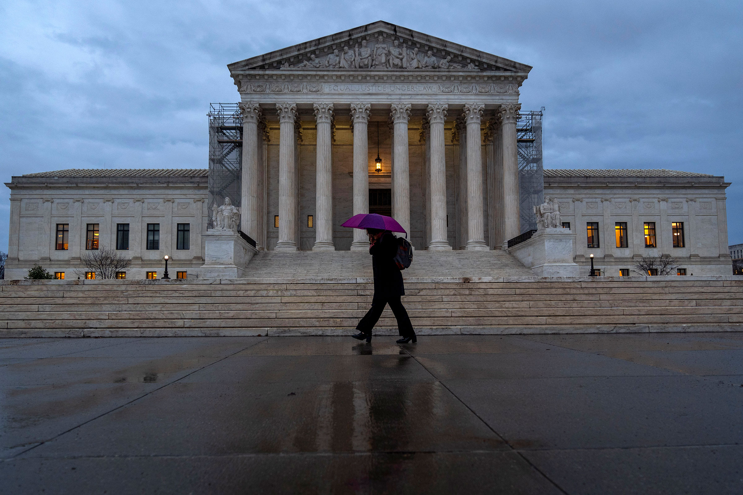 A woman under a purple umbrella walks past the Supreme Court on Wednesday, February 28, in Washington, DC.