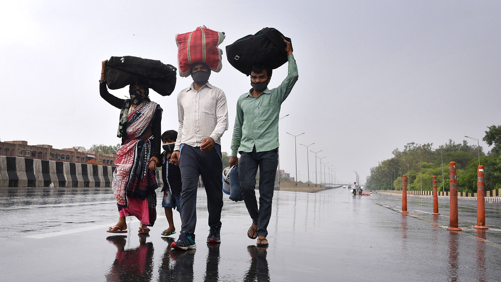 Migrant workers walk towards a bus stop after learning that the administration was preparing to send migrant workers back to their home states during lockdown in New Delhi, India on May 3. 