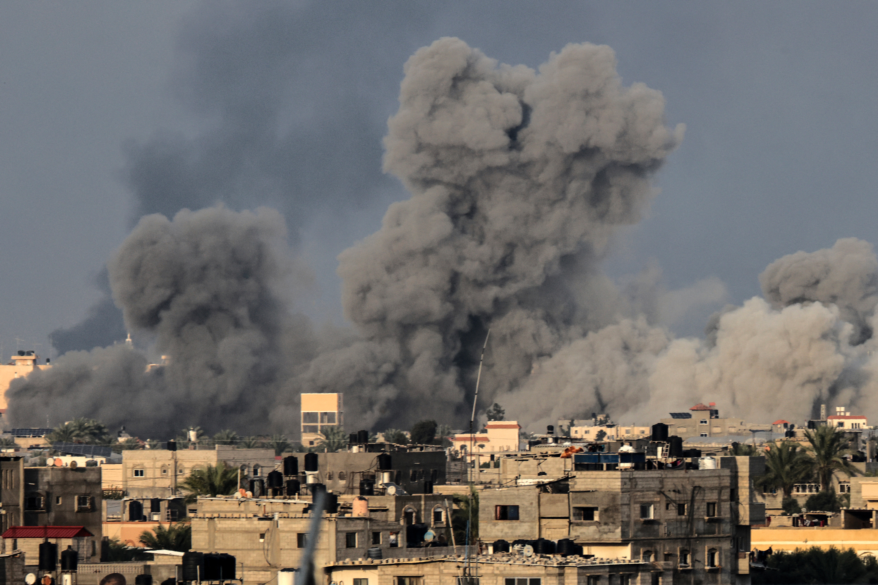 A picture taken from Rafah shows smoke above buildings during Israeli bombardment on Khan Younis, in southern Gaza, on December 7.