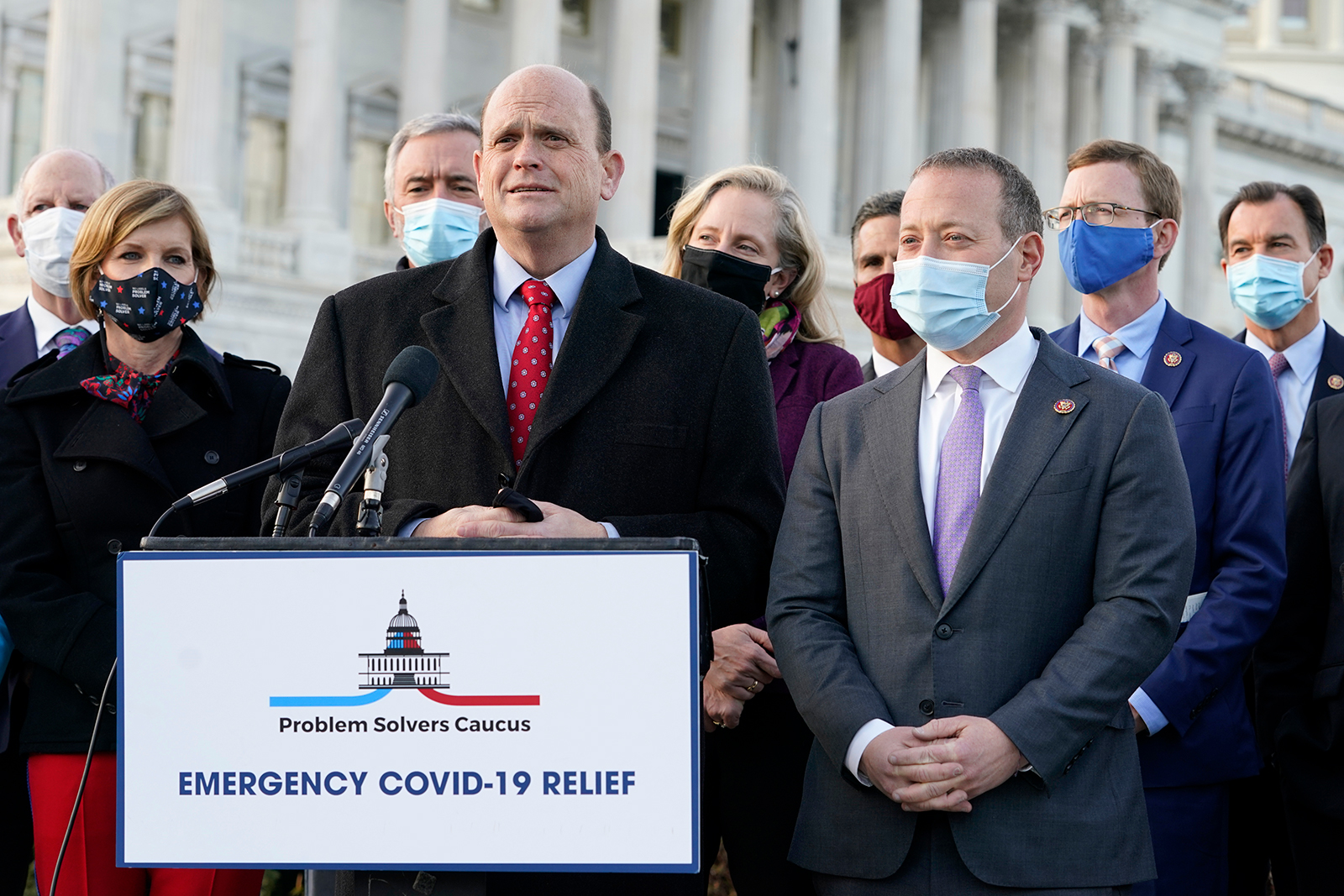 Problem Solvers Caucus co-chairs Rep. Tom Reed, at podium, and Rep. Josh Gottheimer, right, speak to the media with members of their caucus about the expected passage of the emergency Covid-19 relief bill, on Monday at Capitol Hill in Washington.
