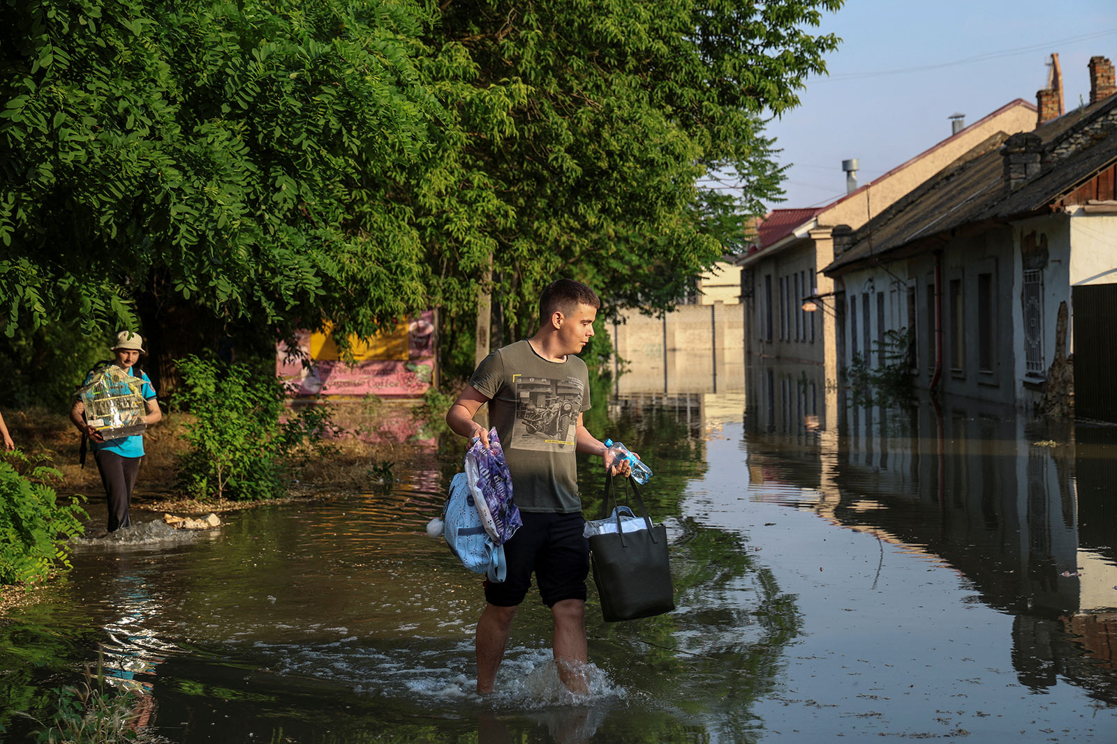 Local residents carry their belongings from a flooded house after the Nova Kakhovka dam breached, in Kherson, Ukraine, on Tuesday, June 6.