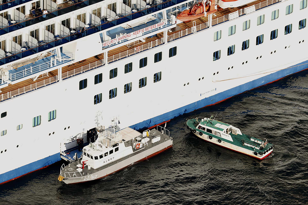 A Japan Coast Guard' patrol boat, left, is brought alongside the cruise ship Diamond Princess to take passengers tested positive for coronavirus to hospitals off Yokohama on Wednesday, February 5.