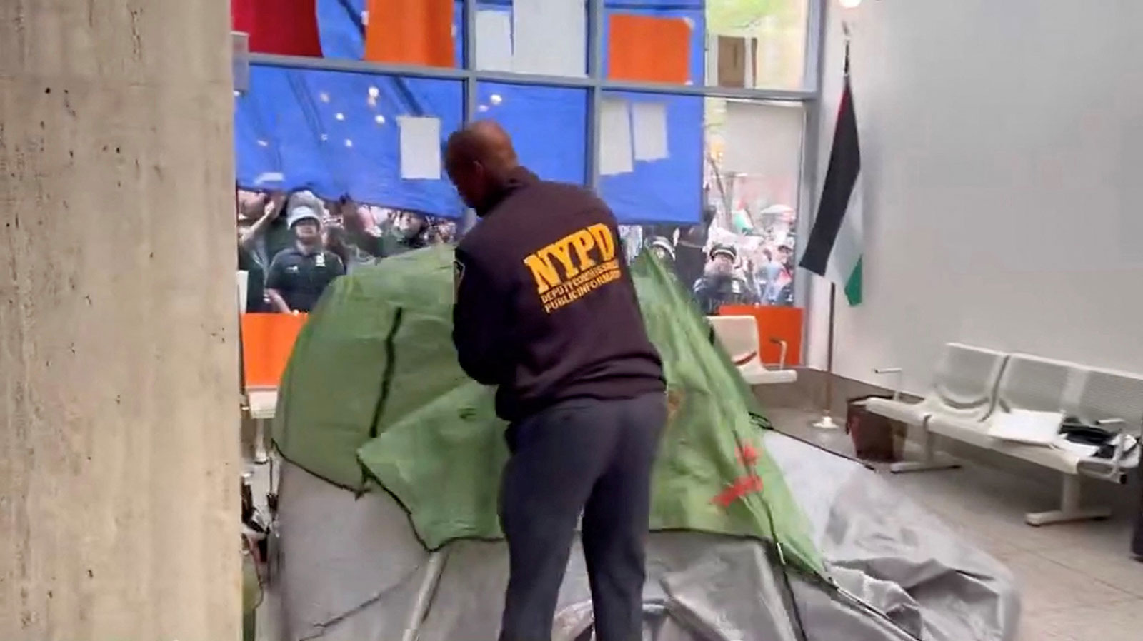 A NYPD officer removes a tent set up by pro-Palestinian protesters inside a building of the Fordham University,  in New York on Wednesday, May 1.