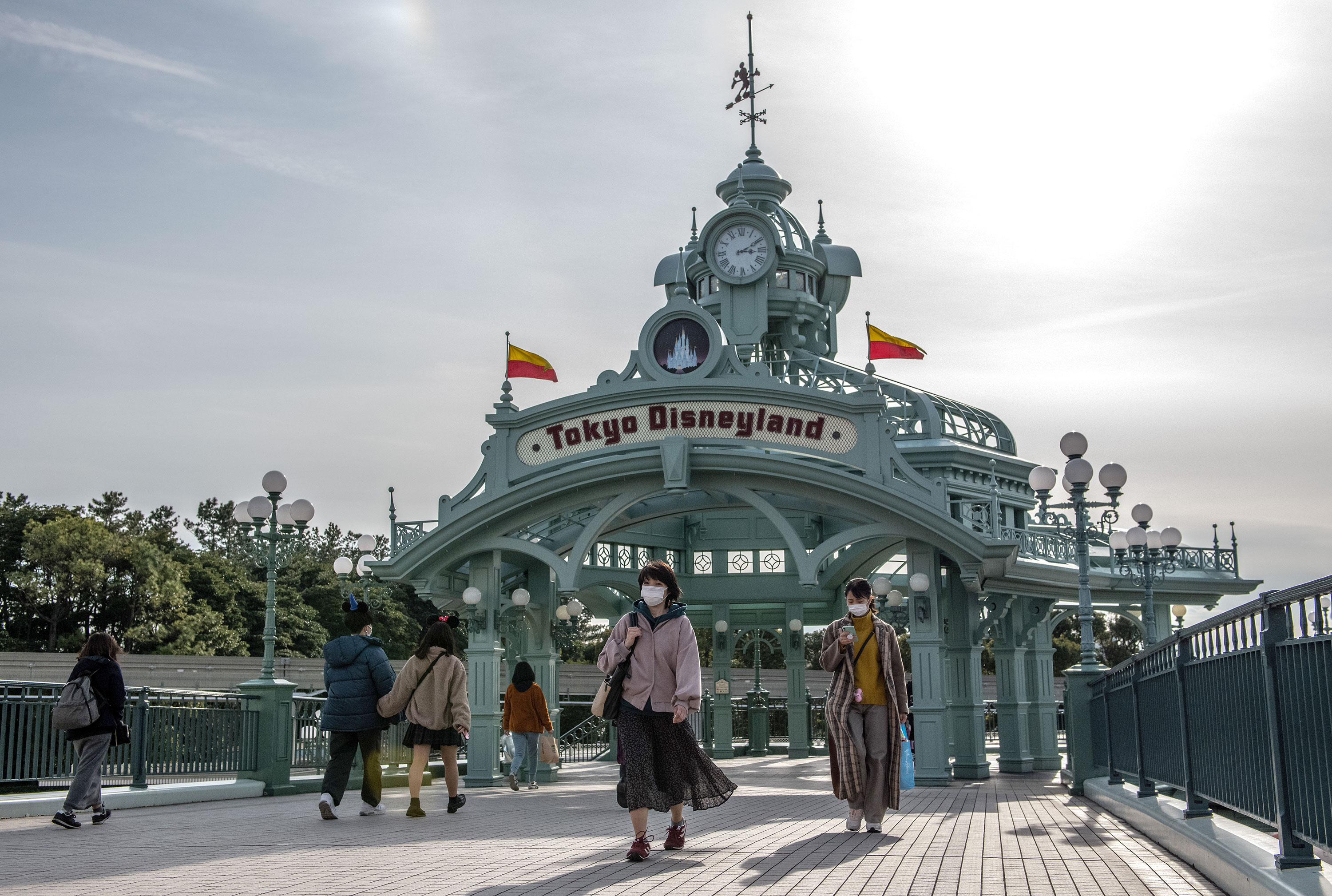 People pass beneath an archway leading to Tokyo Disneyland on February 28.