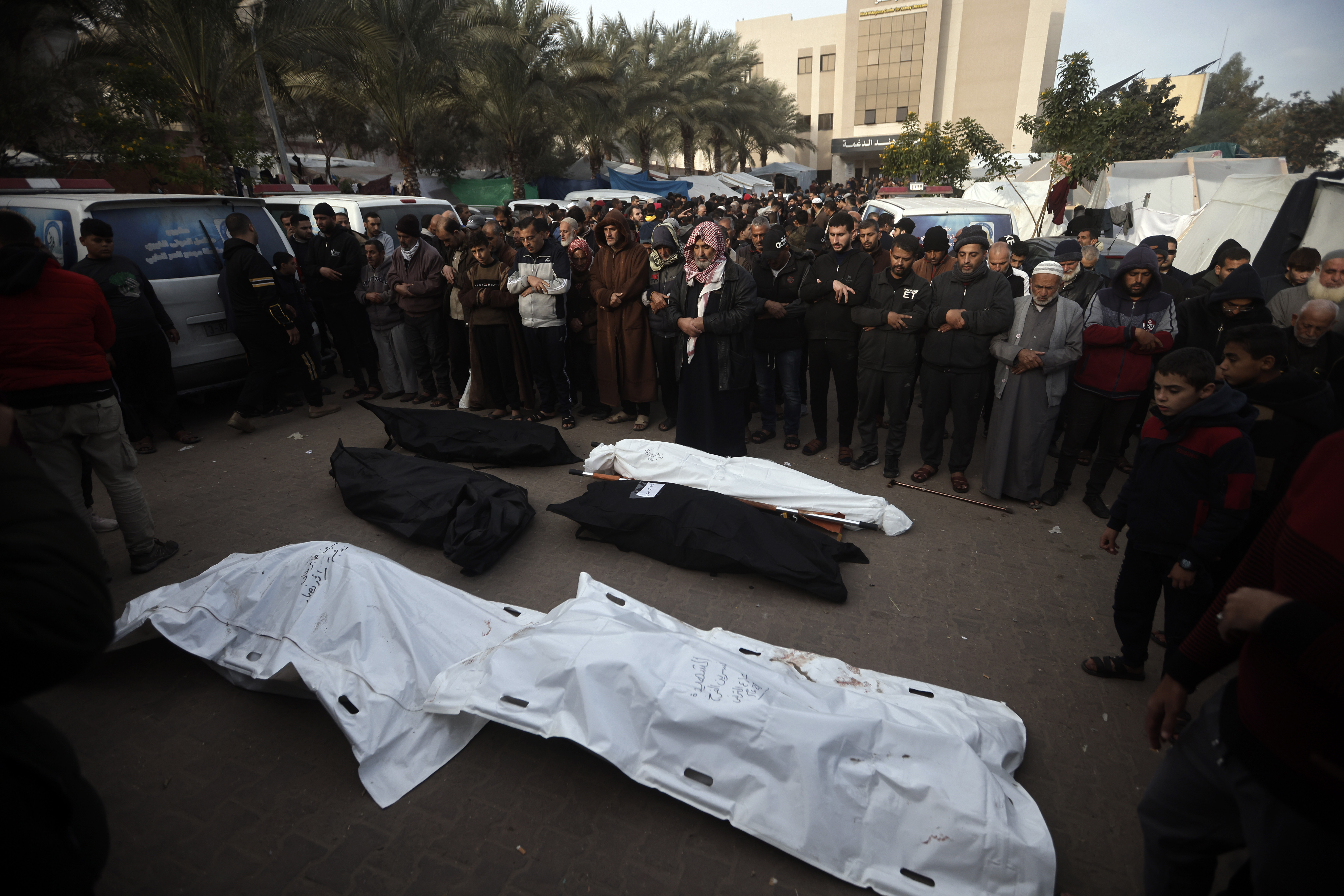 Palestinians outside a morgue in Khan Younis, Gaza, pray near the wrapped bodies of relatives killed in the Israeli bombardment on December 20.