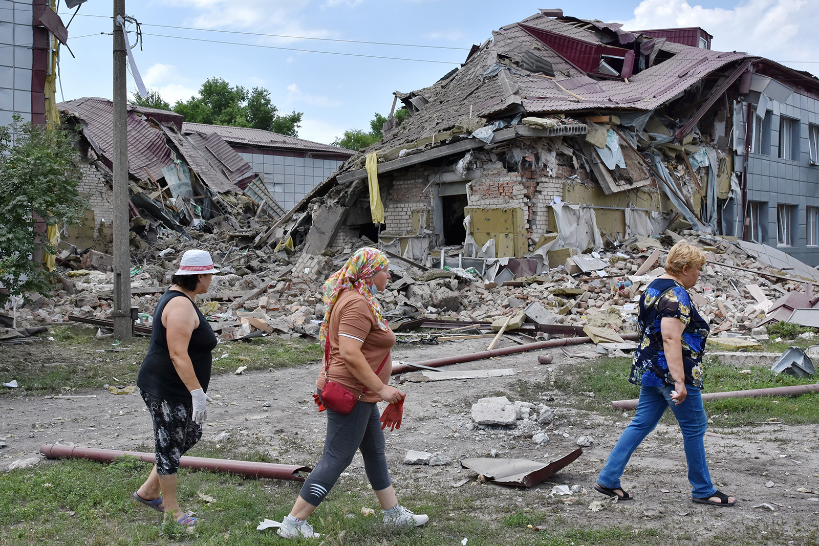 Residents walk by a school that was damaged by Russian shelling in Kamyshevakha, Ukraine, on July 2. 