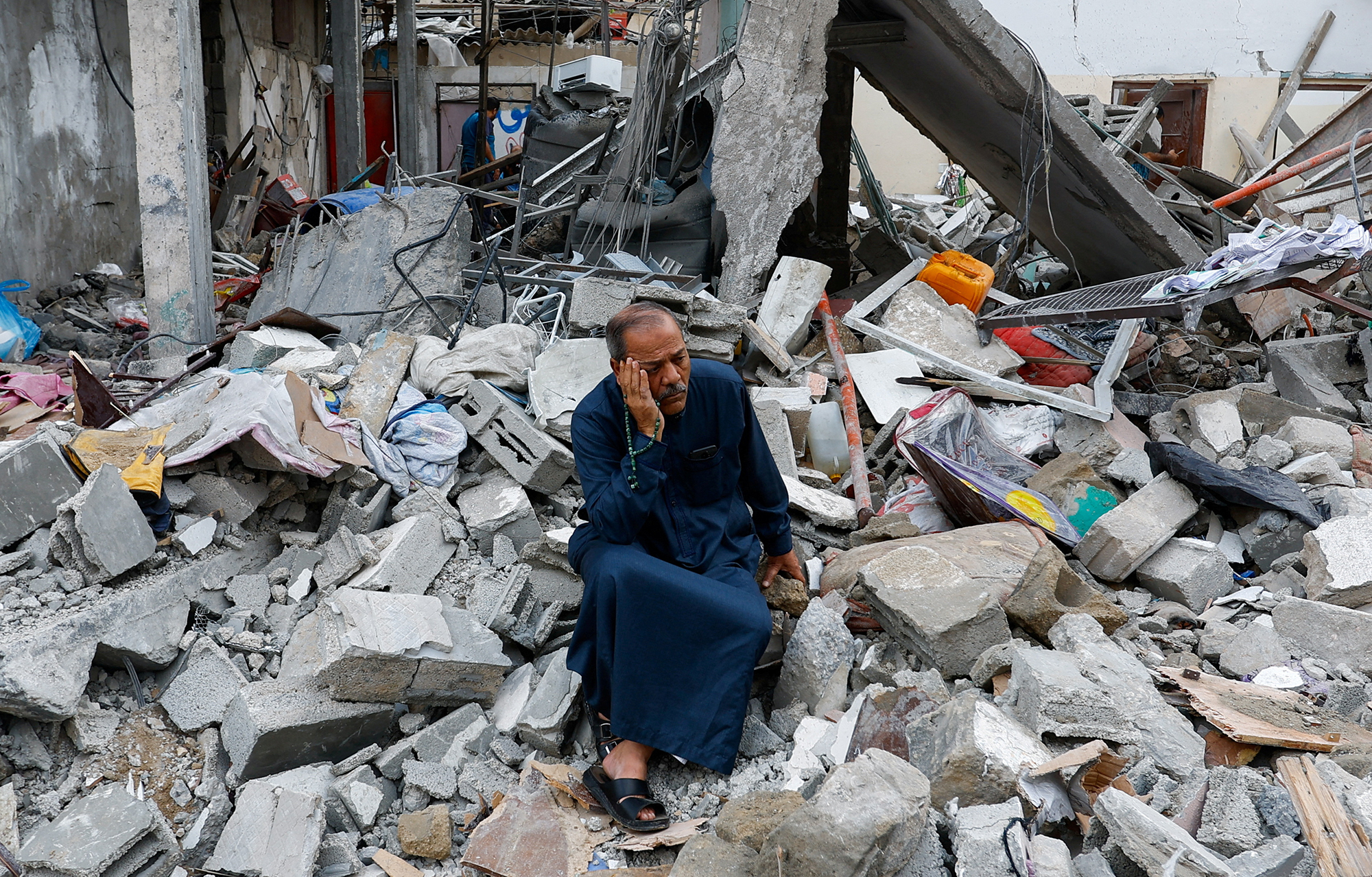 A Palestinian sits on the rubble of a building destroyed in Israeli strikes, in Rafah, southern Gaza, on October 9, 2023.