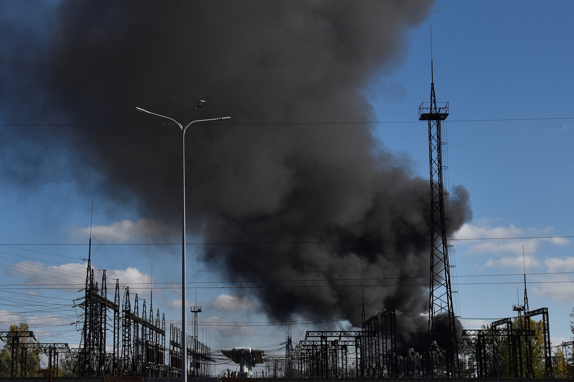 Smoke rises over power lines after Russian missile strikes in Lviv, Ukraine, on October 10.
