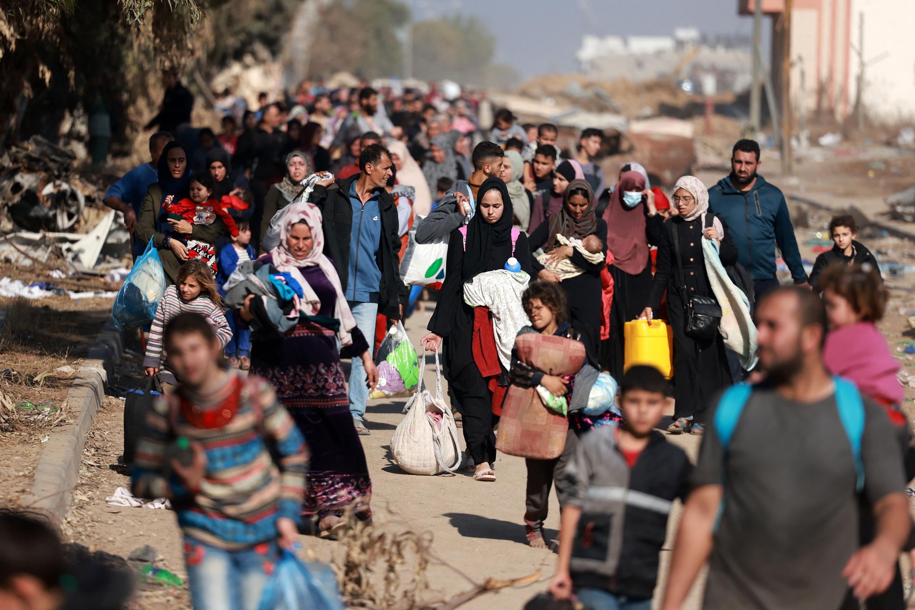 Palestinians fleeing Gaza City and other parts of northern Gaza, carry some belongings as they walk along a road leading to the southern areas of the enclave on November 18.