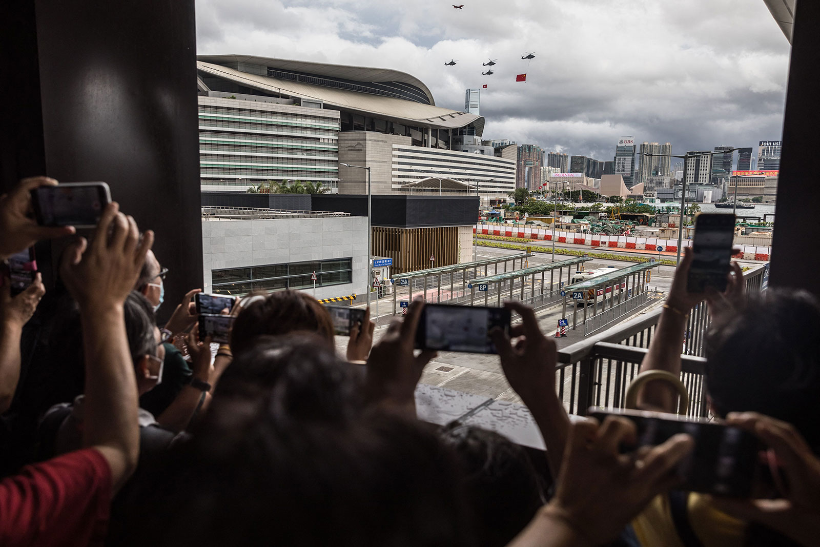 People watch as helicopters and an aircraft fly past during a flag raising ceremony to celebrate the 25th anniversary of the city's handover from Britain to China, in Hong Kong on July 1.