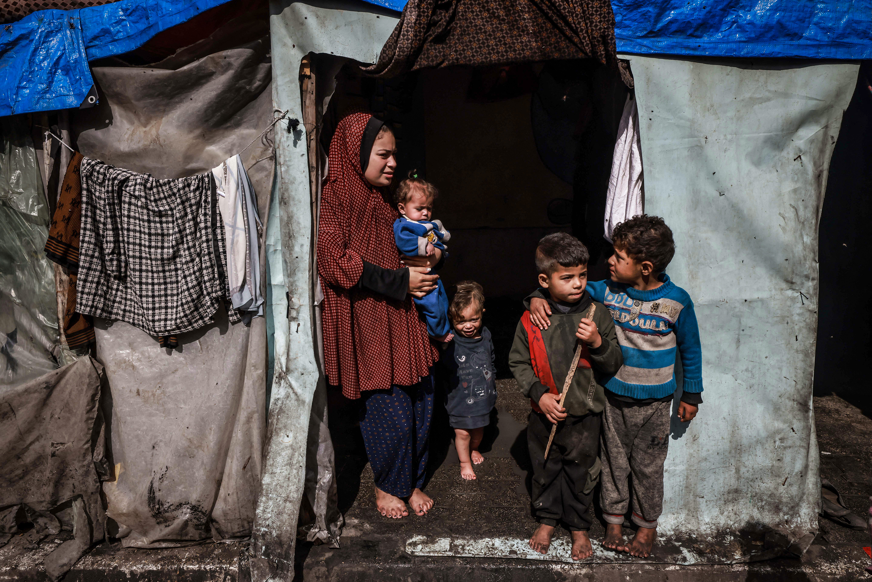 A displaced Palestinian woman and children wait at the entrance of a makeshift tent at a camp in Rafah on March 14. 